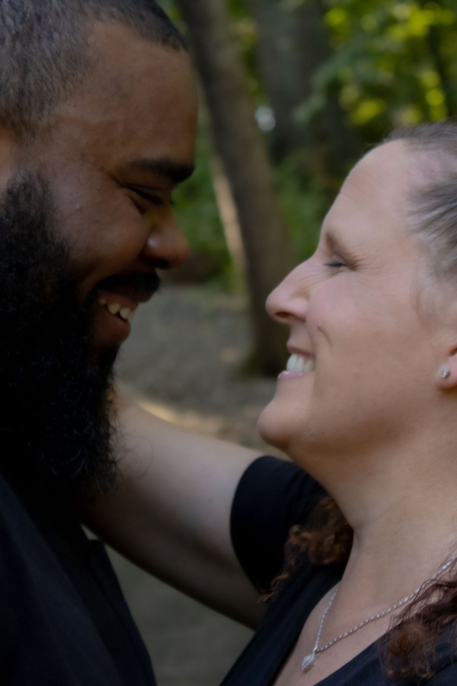 A couple sharing a joyful close moment outdoors with genuine laughter.