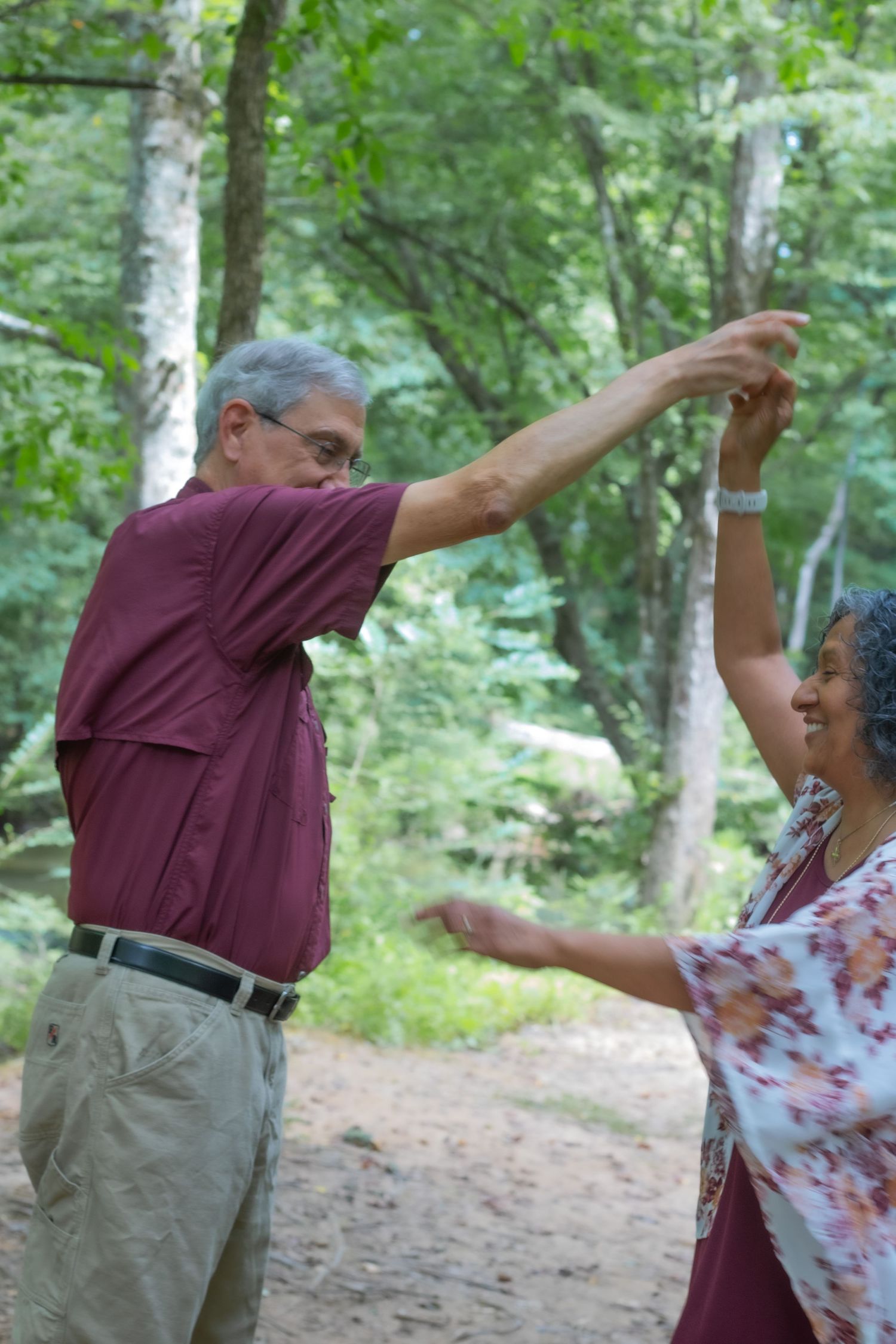 Two people dancing joyfully together on a forest path.