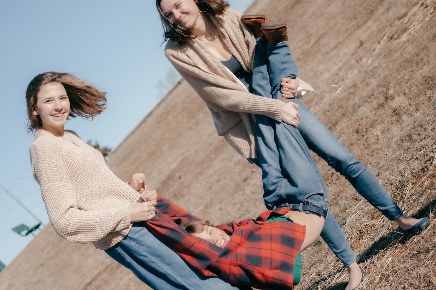 A couple spins and dances joyfully together in a grassy outdoor setting during a candid photoshoot.