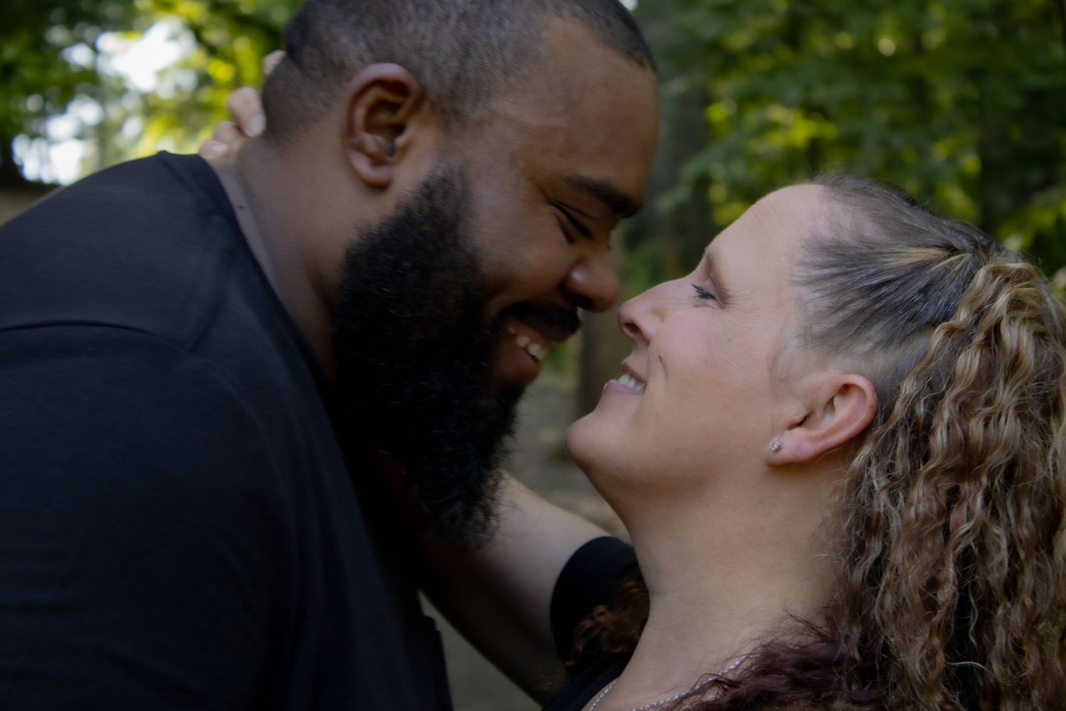 A tender moment shared between two people in an outdoor garden setting.