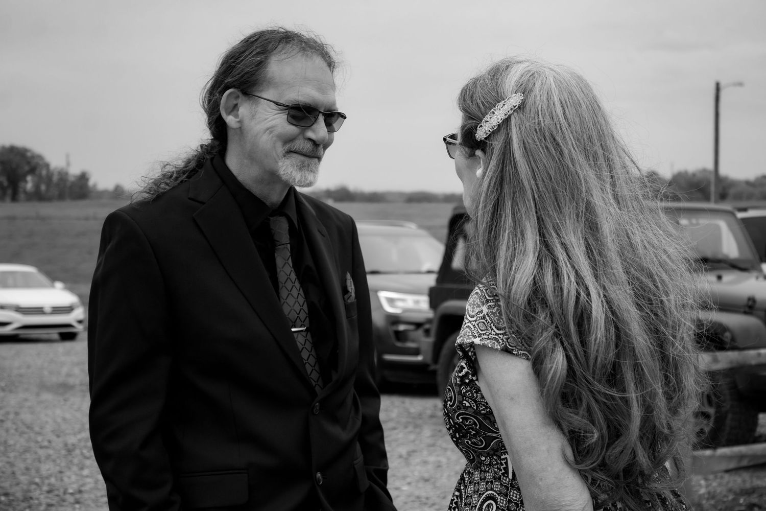 Black and white candid photo of two guests in formal attire sharing conversation.