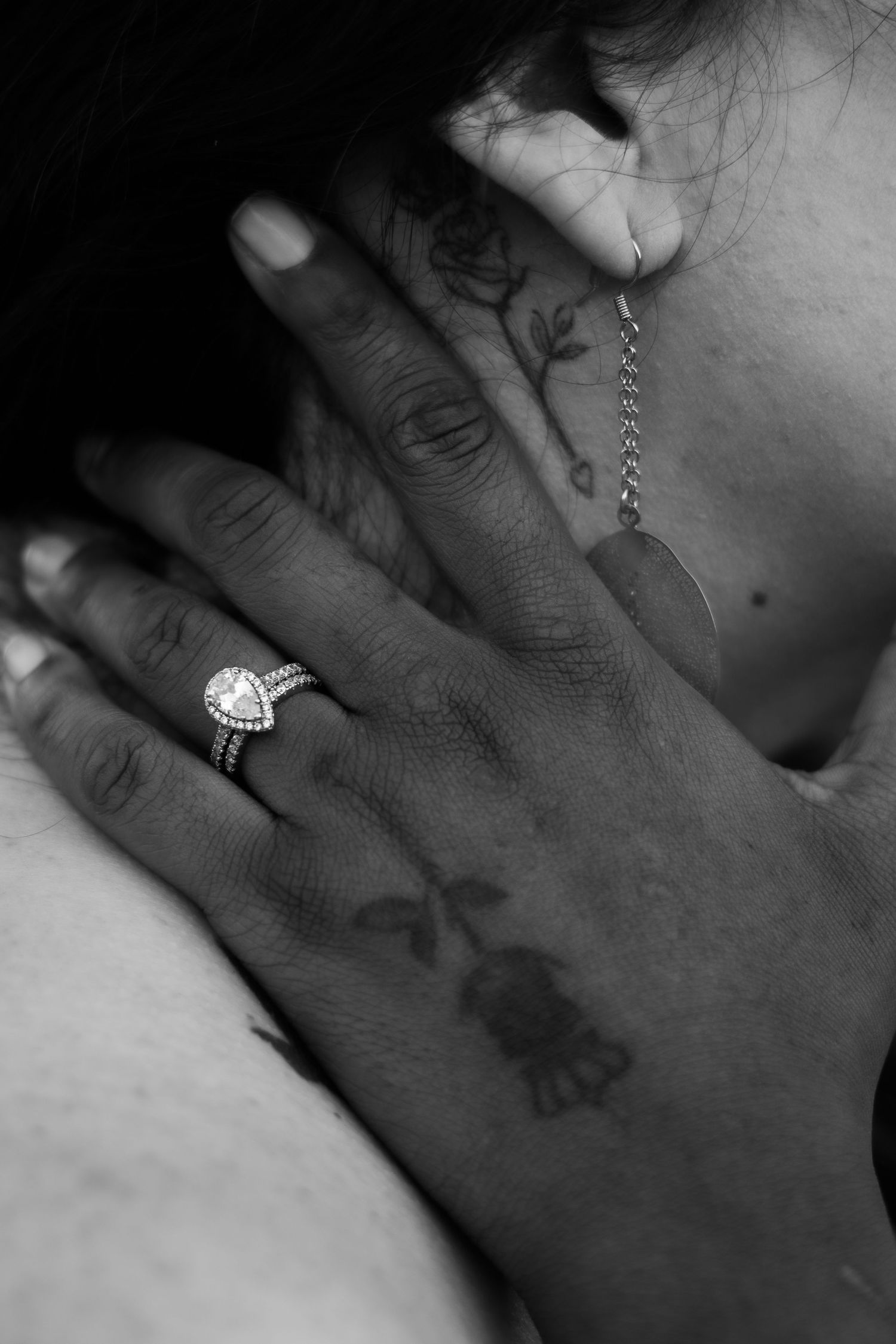 Black and white close-up of a hand wearing a heart-shaped engagement ring.