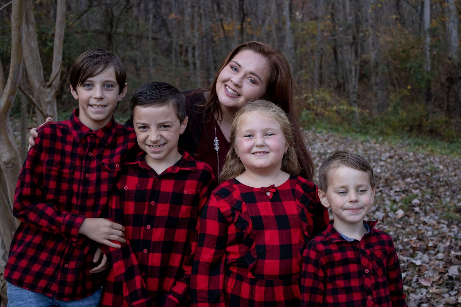 A cheerful group in coordinating red buffalo plaid shirts smiles for a casual outdoor portrait.