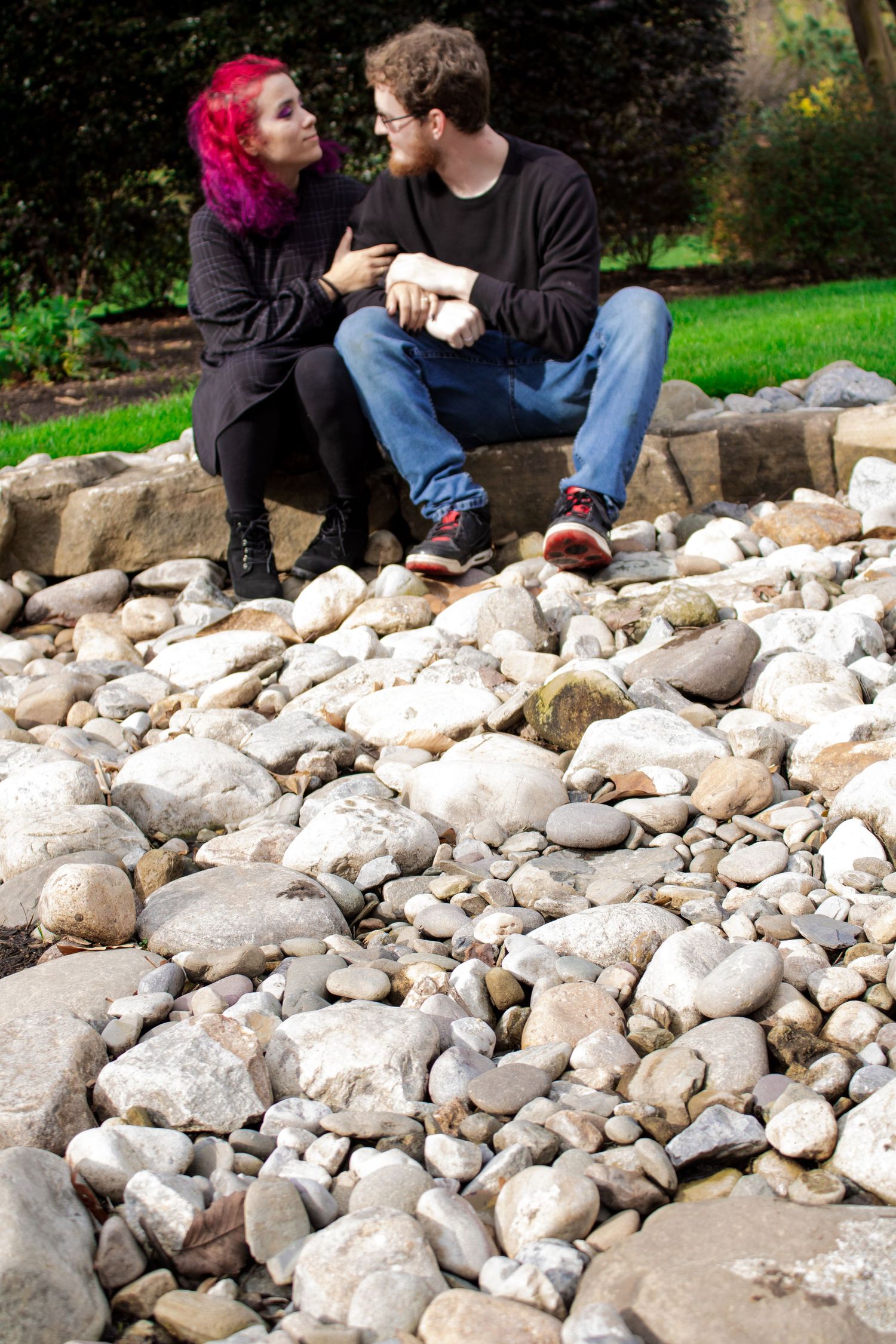 A couple sitting on rocky terrain having an intimate conversation while holding cups.
