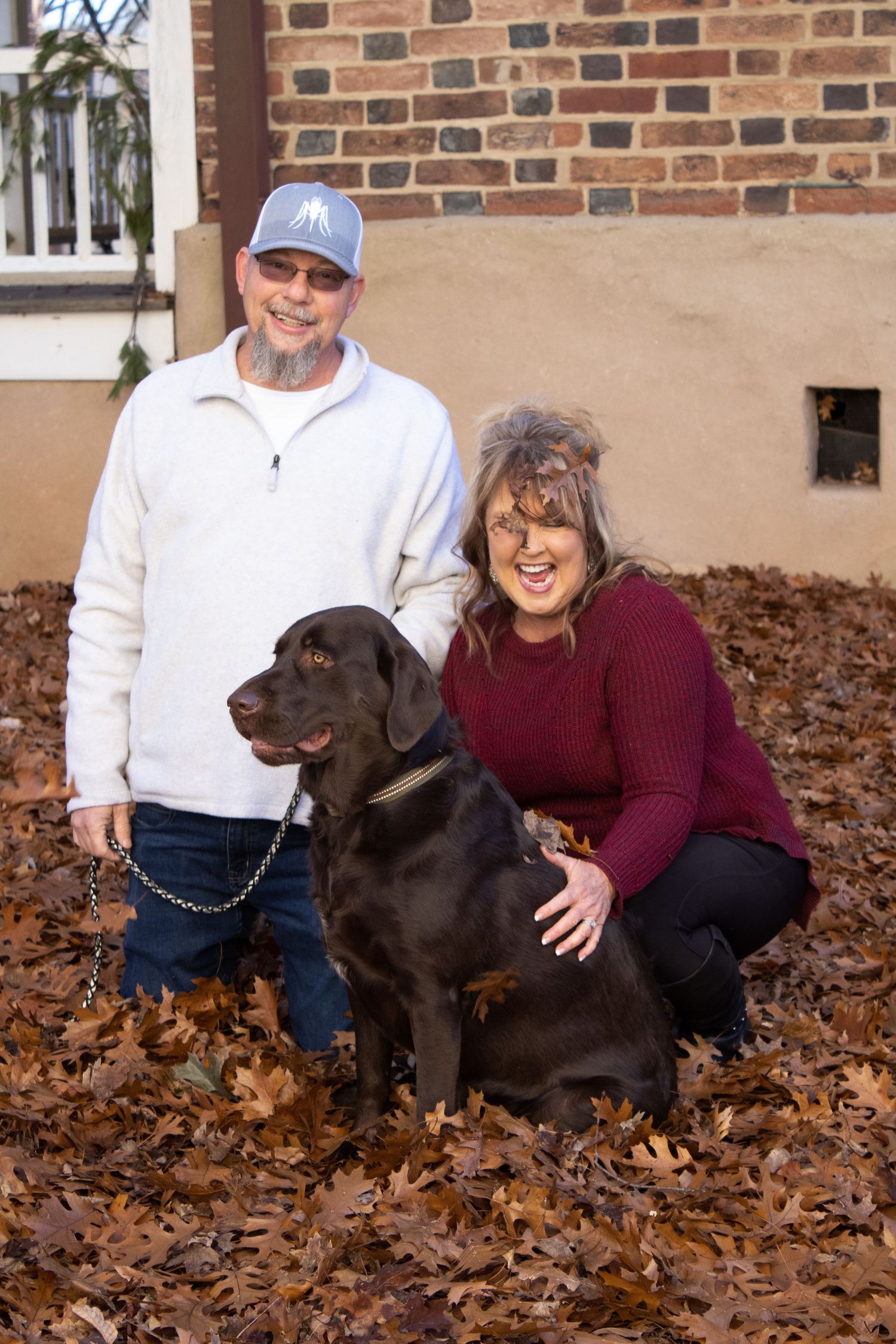 Family photo with black Labrador dog among fallen autumn leaves.