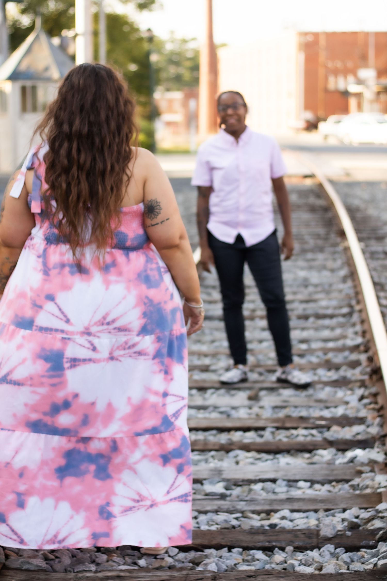 Couple facing each other on train tracks wearing coordinated casual attire.