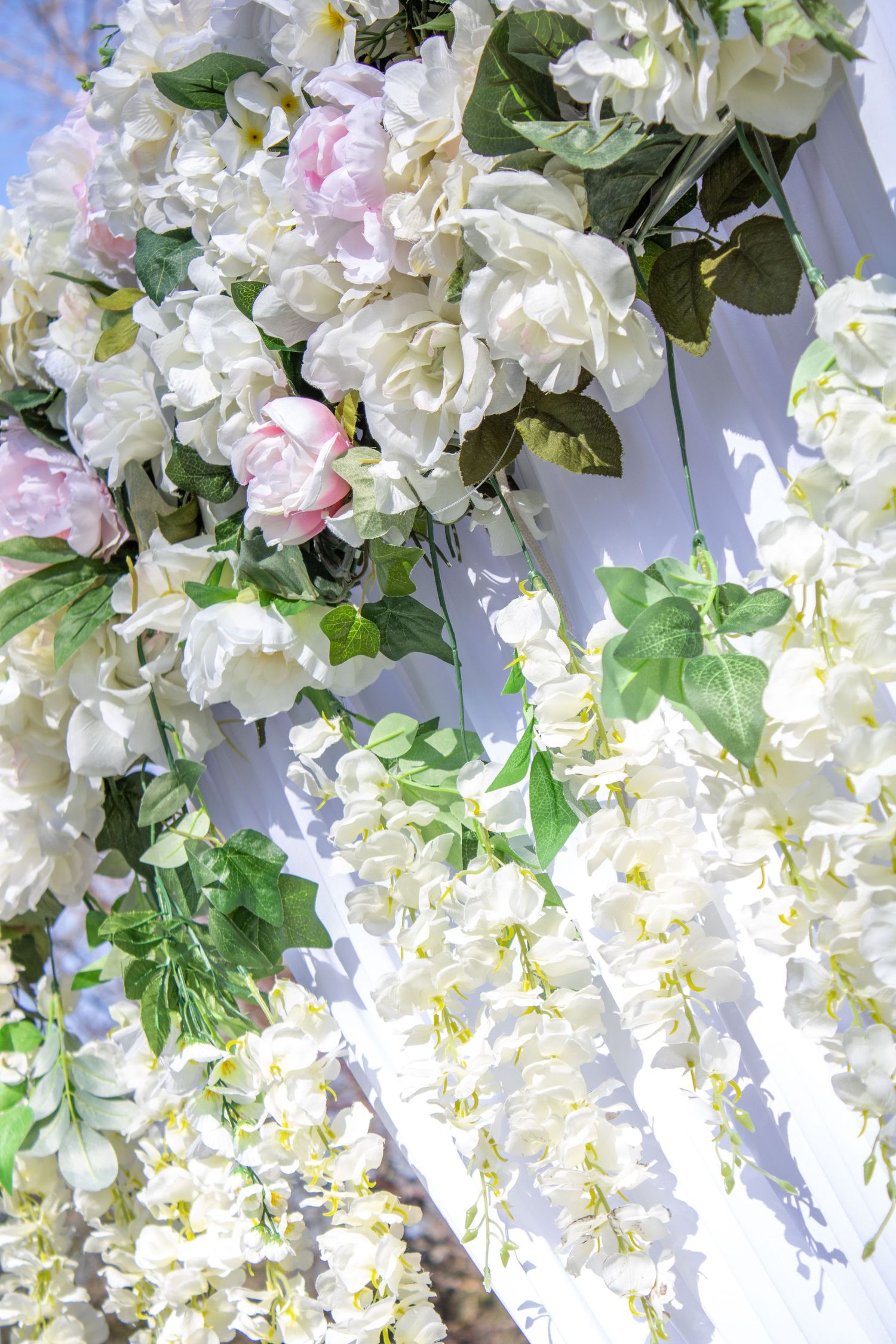 Luxurious white and pink floral arrangement with roses and greenery against a bright background.
