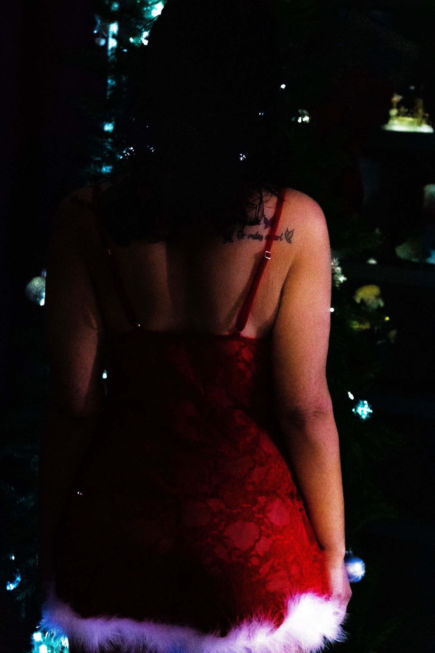 Dramatic red dress with white fur trim photographed against dark background with twinkling lights.