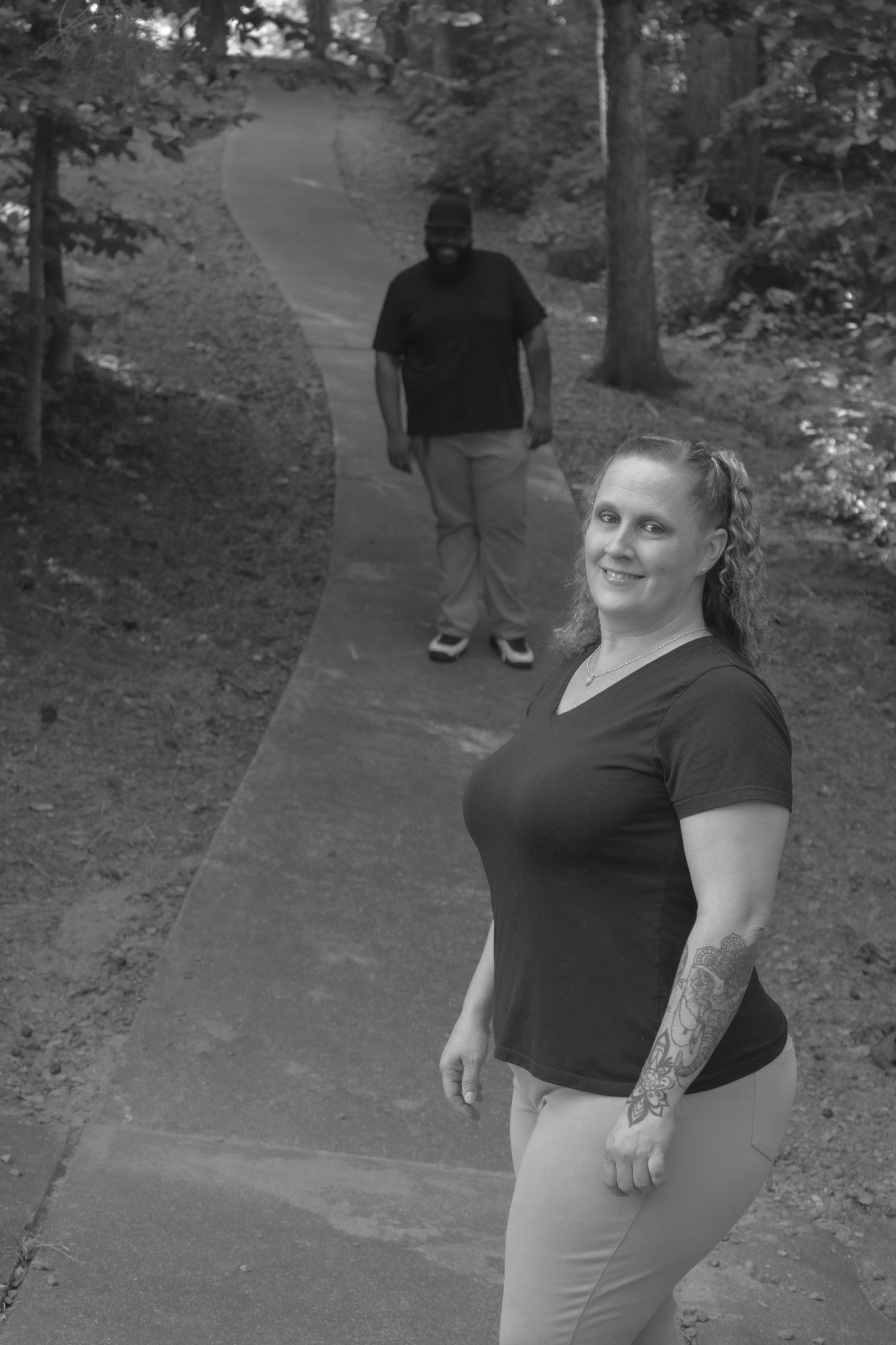 People dressed in black tops and khaki pants pose together on a wooded path.