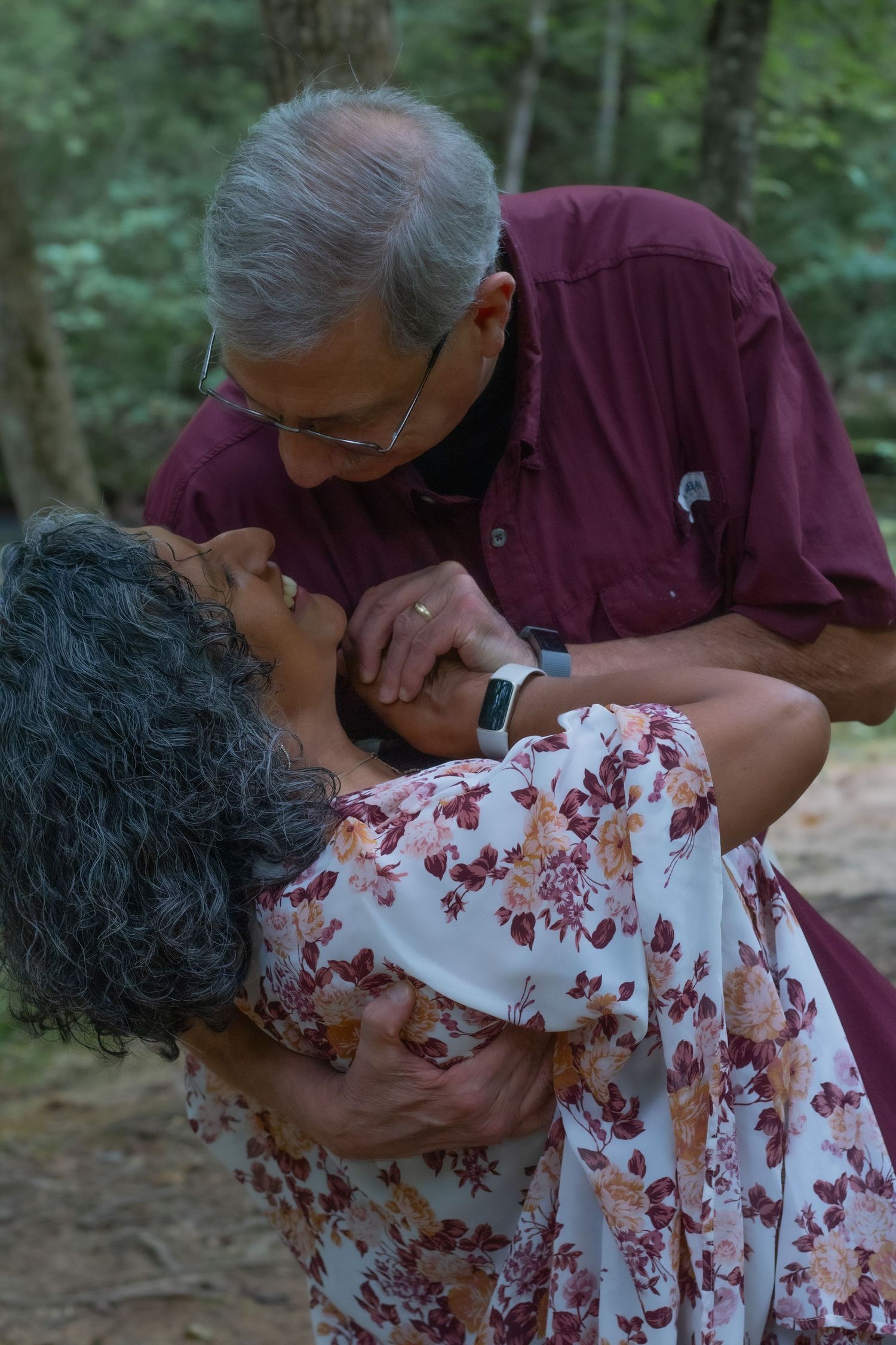 A romantic outdoor moment between two people in a wooded setting.