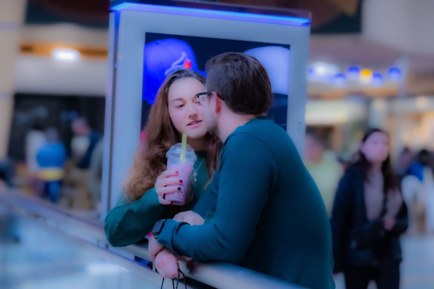 People embracing in a dimly lit indoor space with blue ambient lighting.