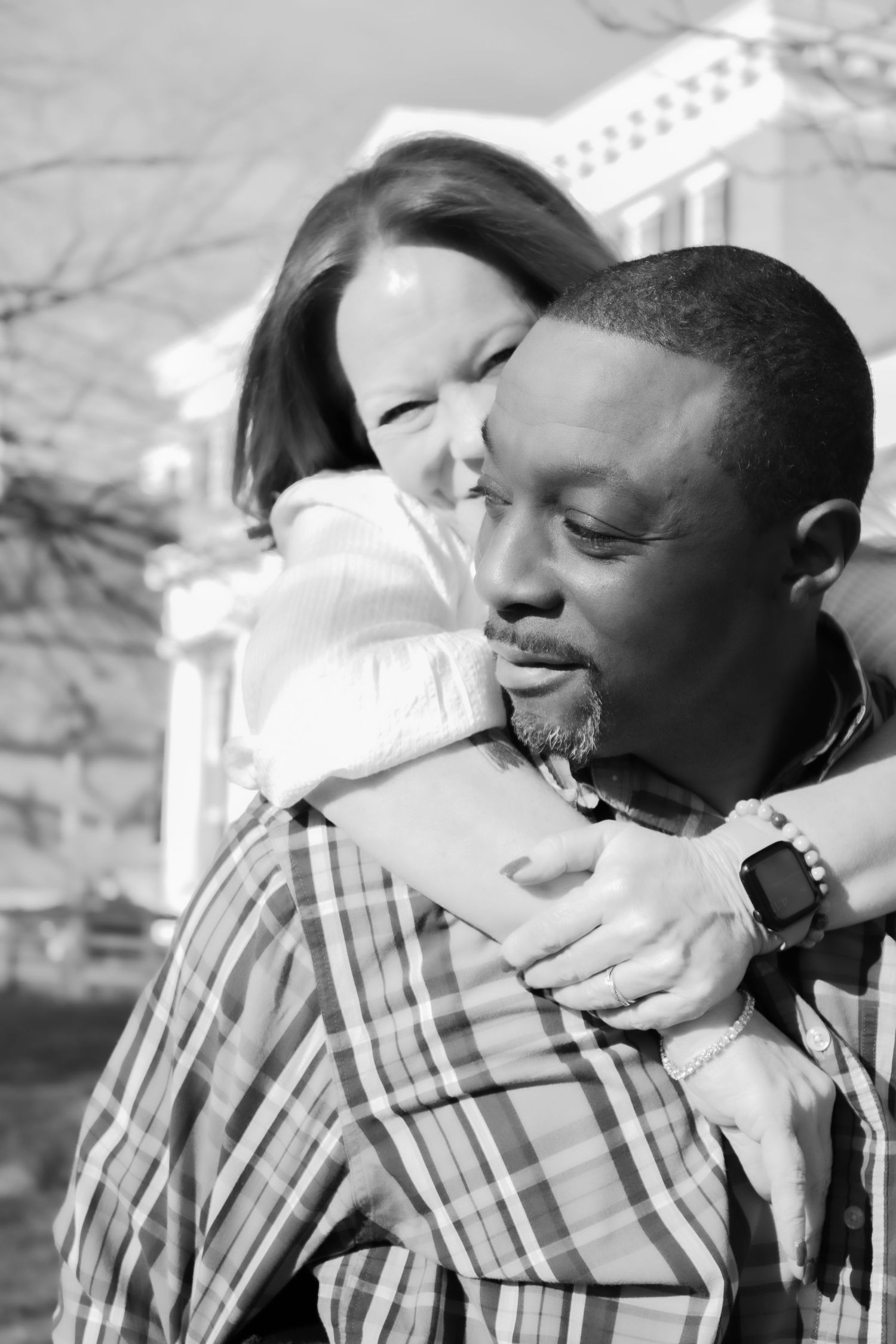 A romantic couple sharing a tender embrace outdoors on a sunny day.