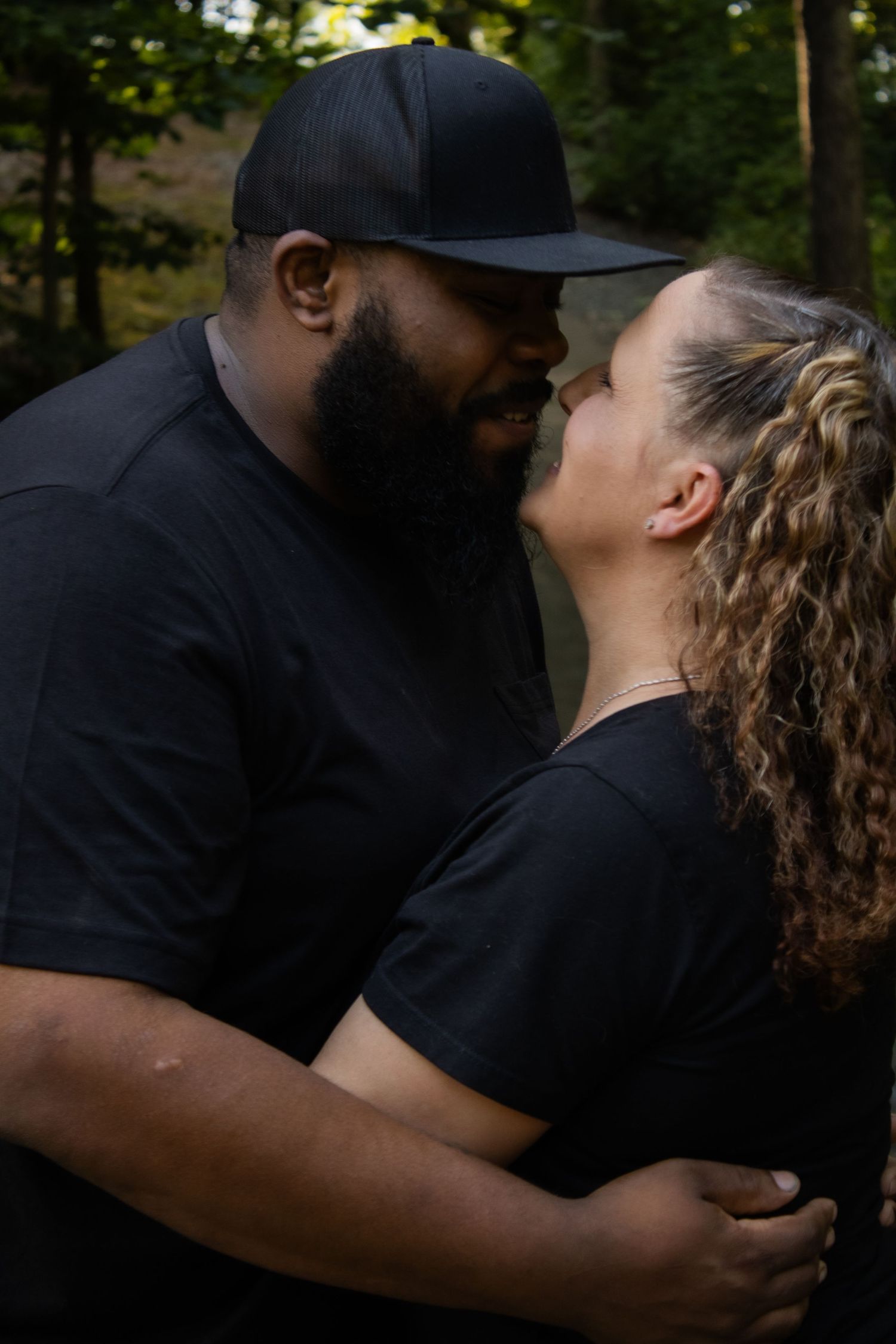 Intimate couple in black clothing sharing a romantic moment outdoors.