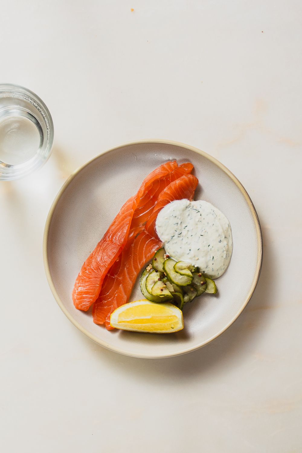 High end restaurant photography flatlay of smoked salmon, pickled cucumber and lemon with water