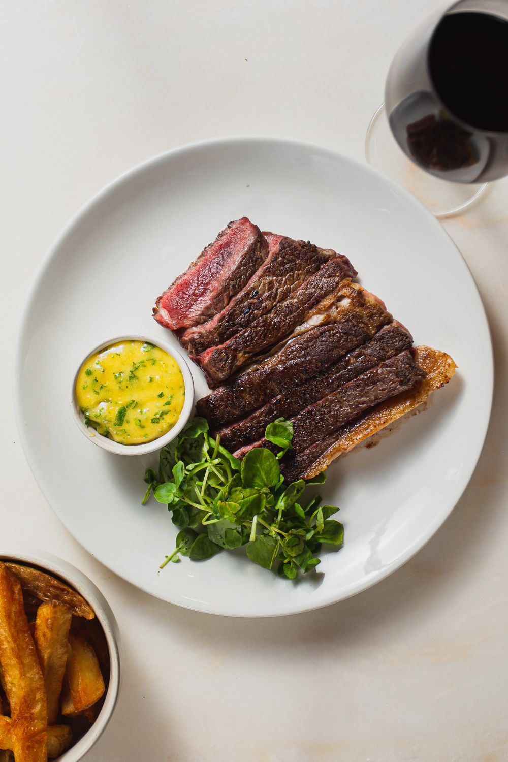 High end restaurant photography flatlay of rare steak with chips and a glass of red wine