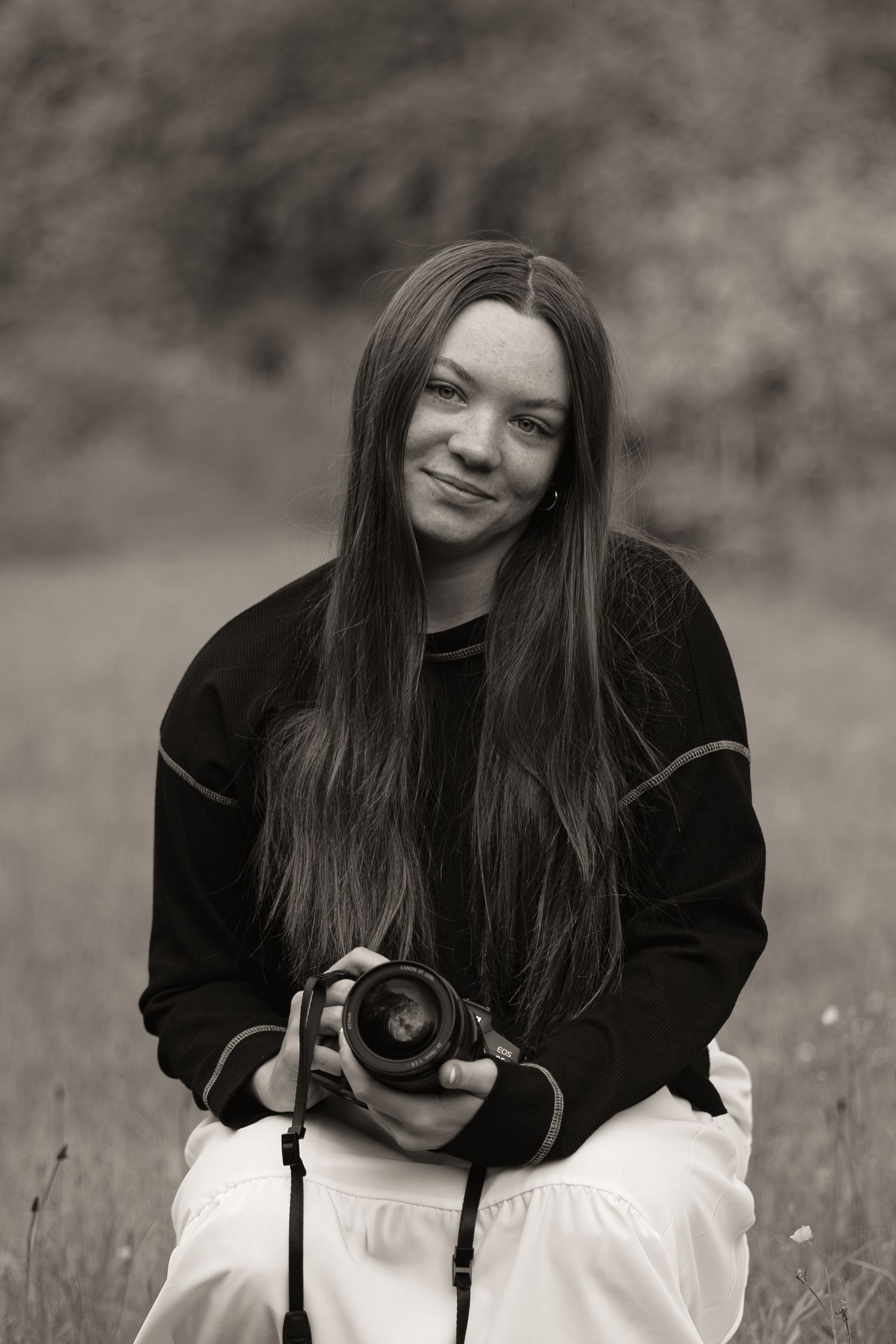 Monochrome portrait of photographer sitting outdoors with professional camera.