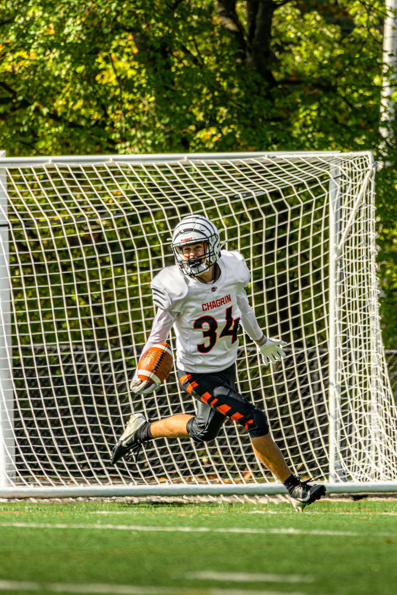Soccer goalkeeper in white uniform diving to make a save during an outdoor match on a sunny day.