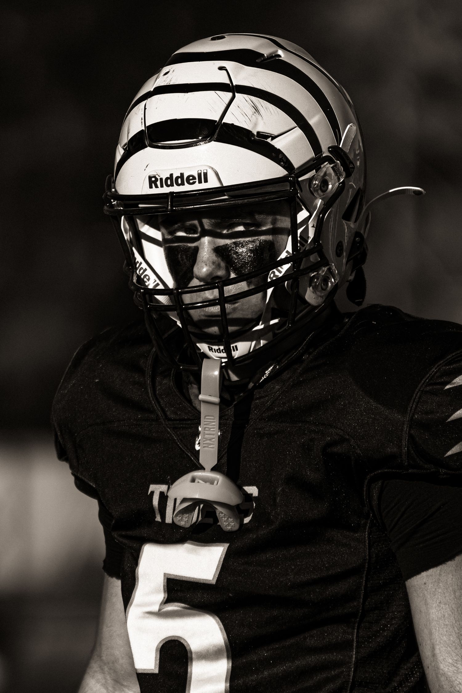 Football player wearing black jersey and white Riddell helmet shown in dramatic black and white photo sequence.