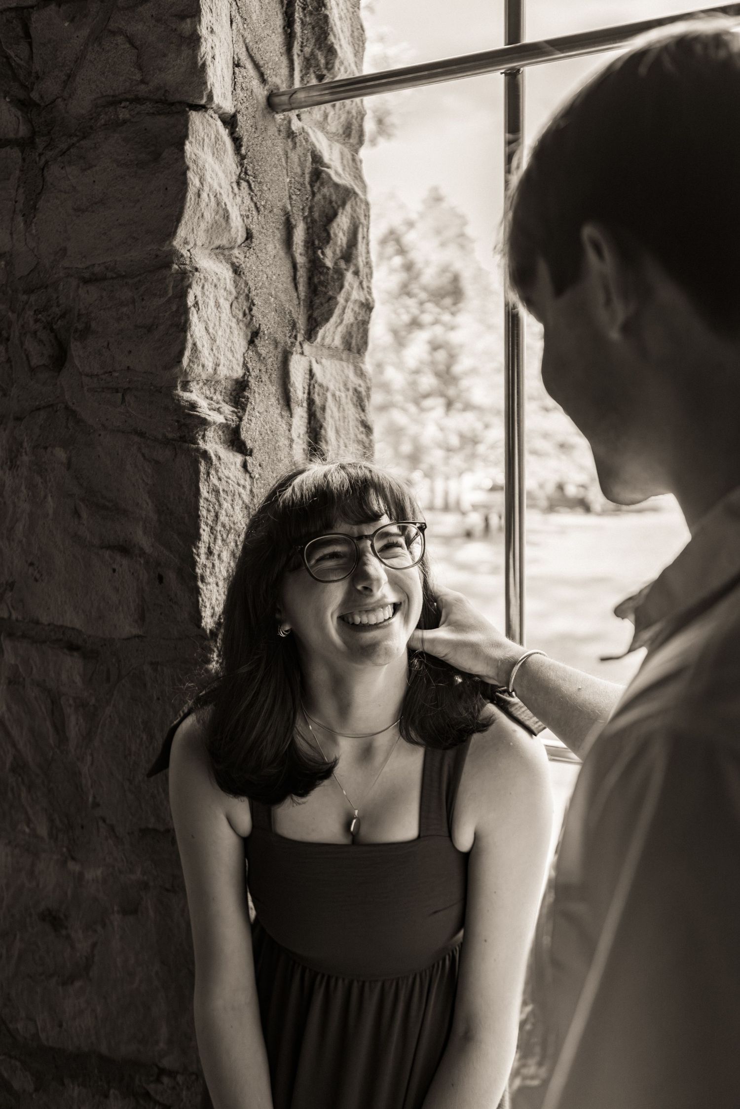 A candid black and white photo series showing a couple sharing joyful moments in a stone archway.