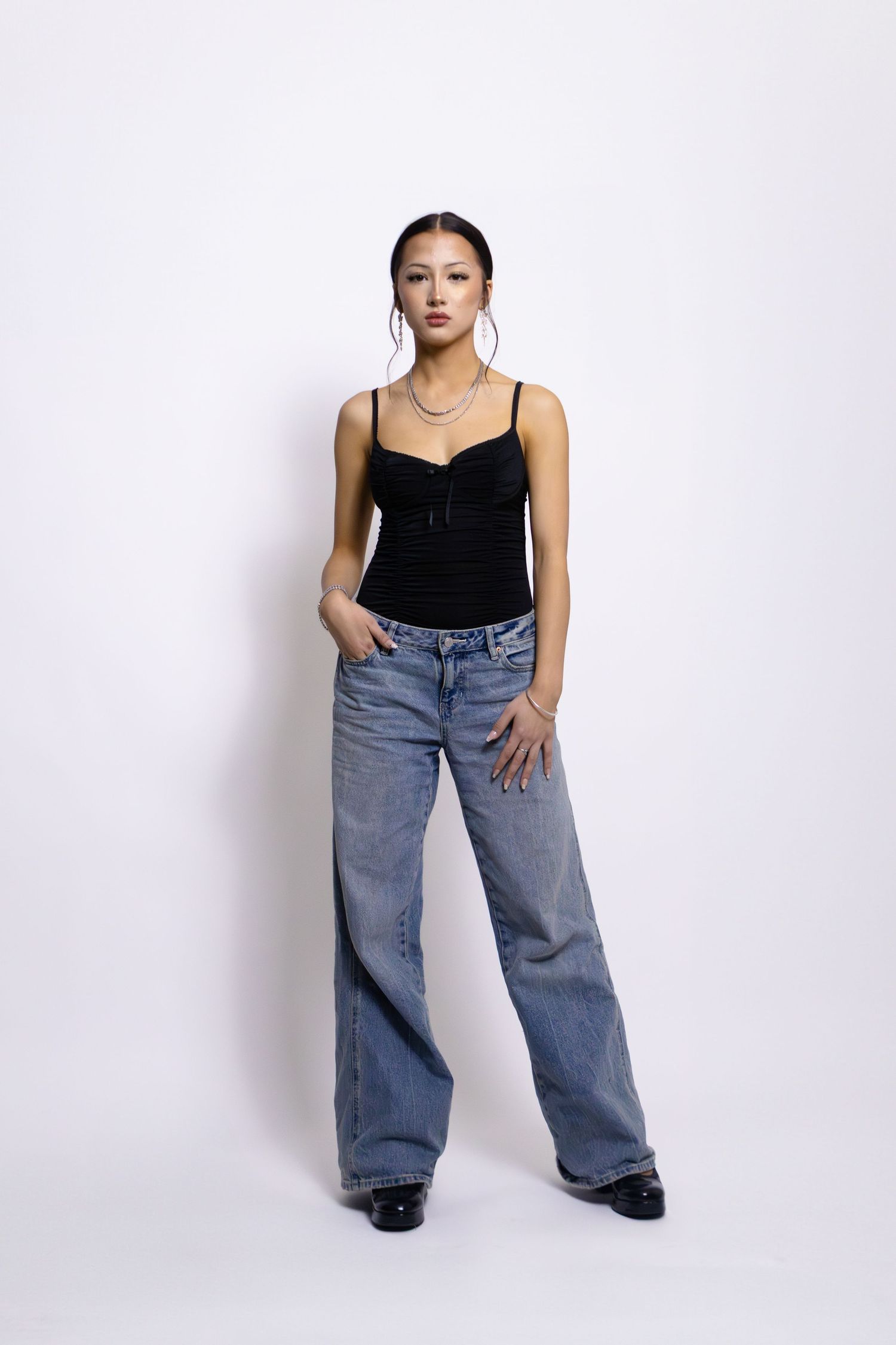 Three fashion poses against white background showing casual outfit with black top and loose-fitting blue jeans.