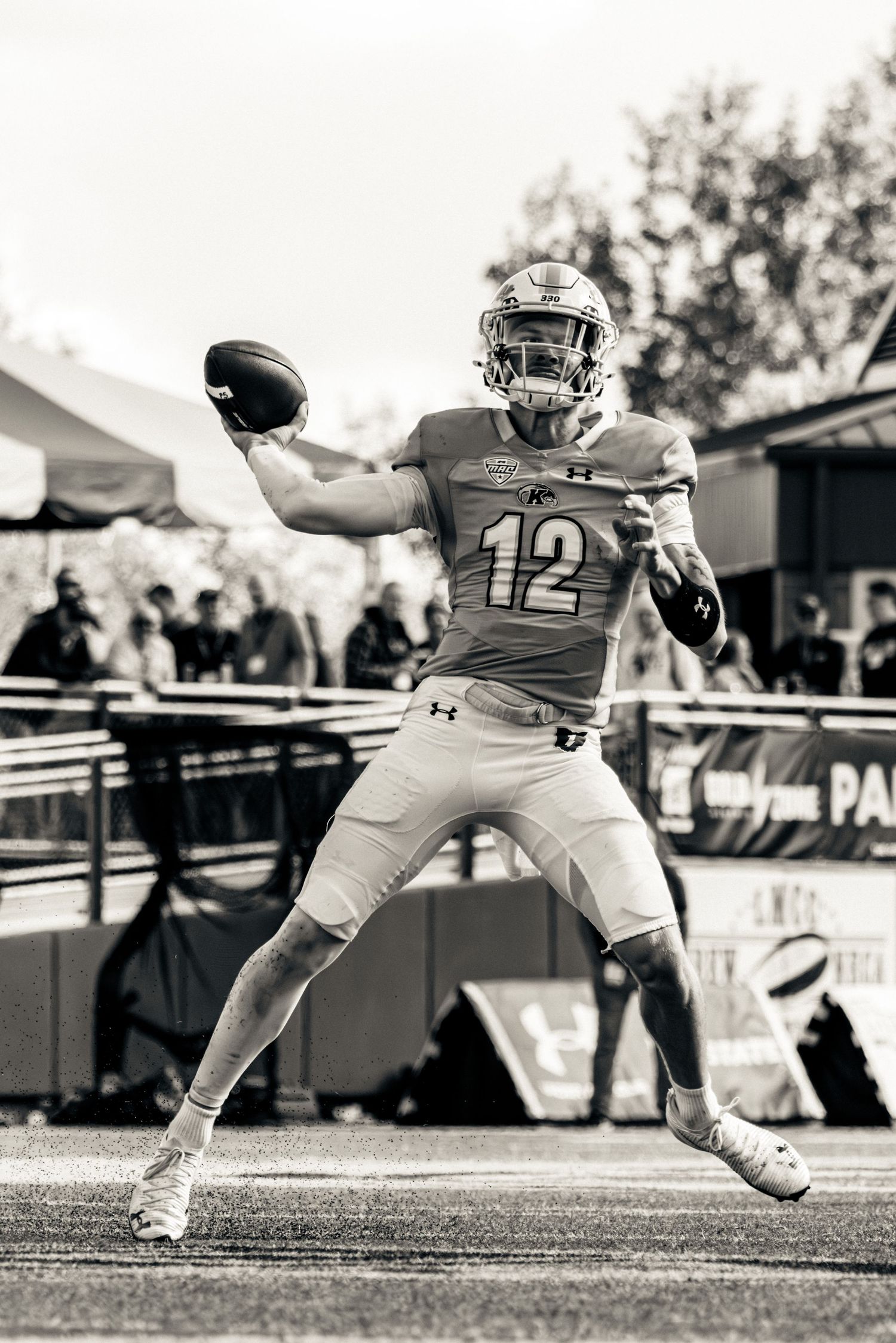 A sequence of three black and white action shots showing a football player kicking a ball during a game.