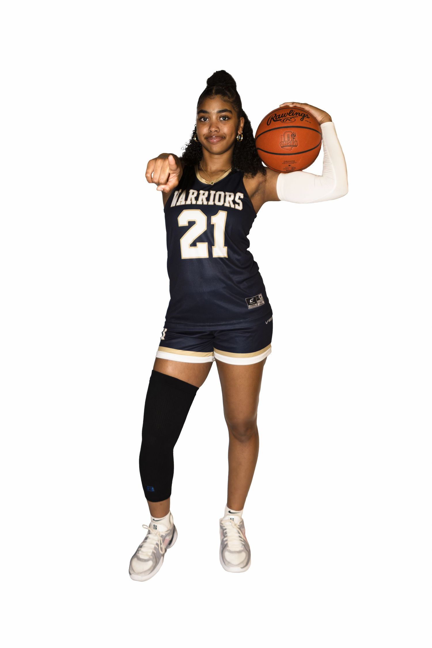 Athlete in Warriors jersey number 21 poses with basketball while wearing knee brace and white sneakers.