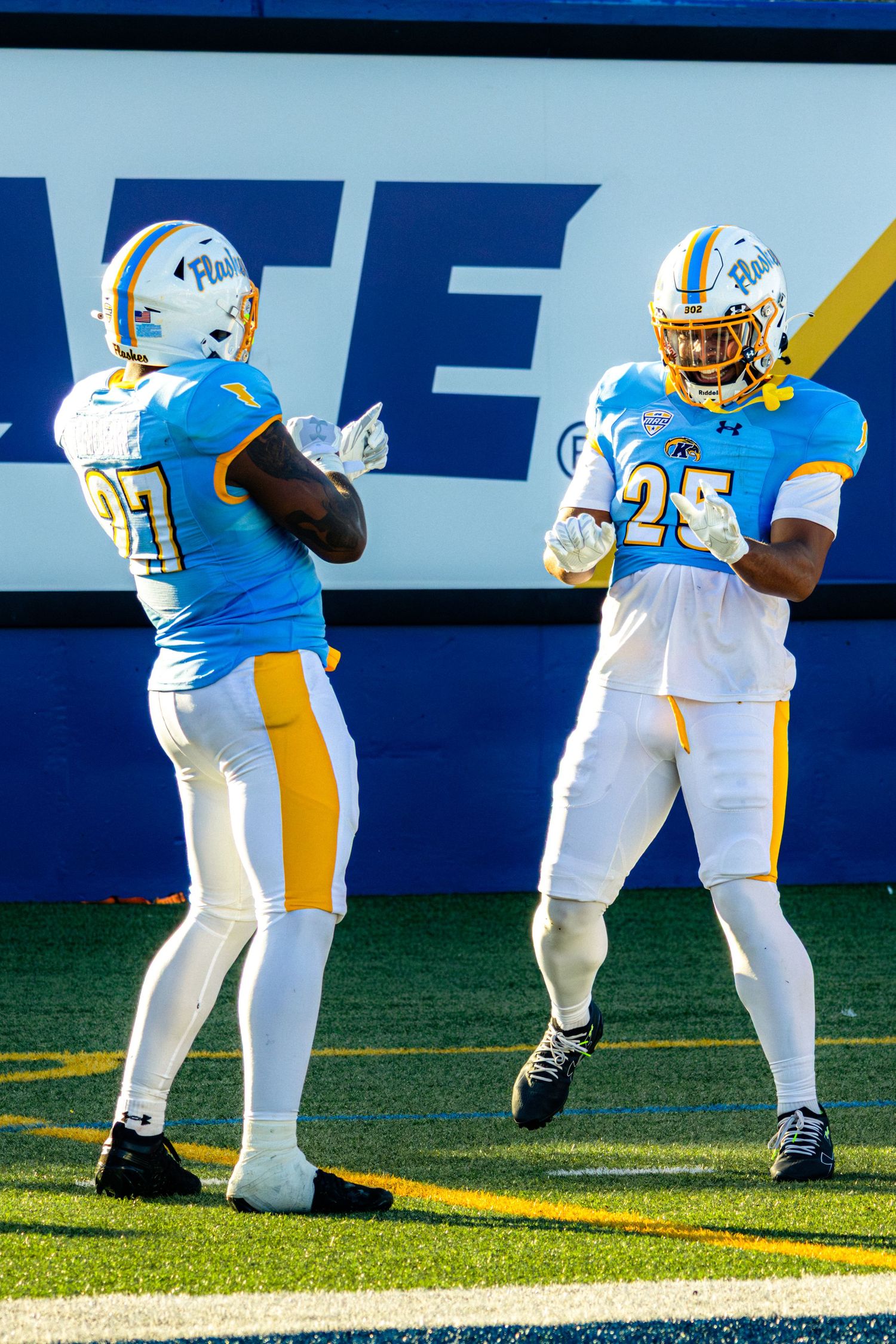 Two Southern University football players in light blue and white uniforms warm up on the field before a game.