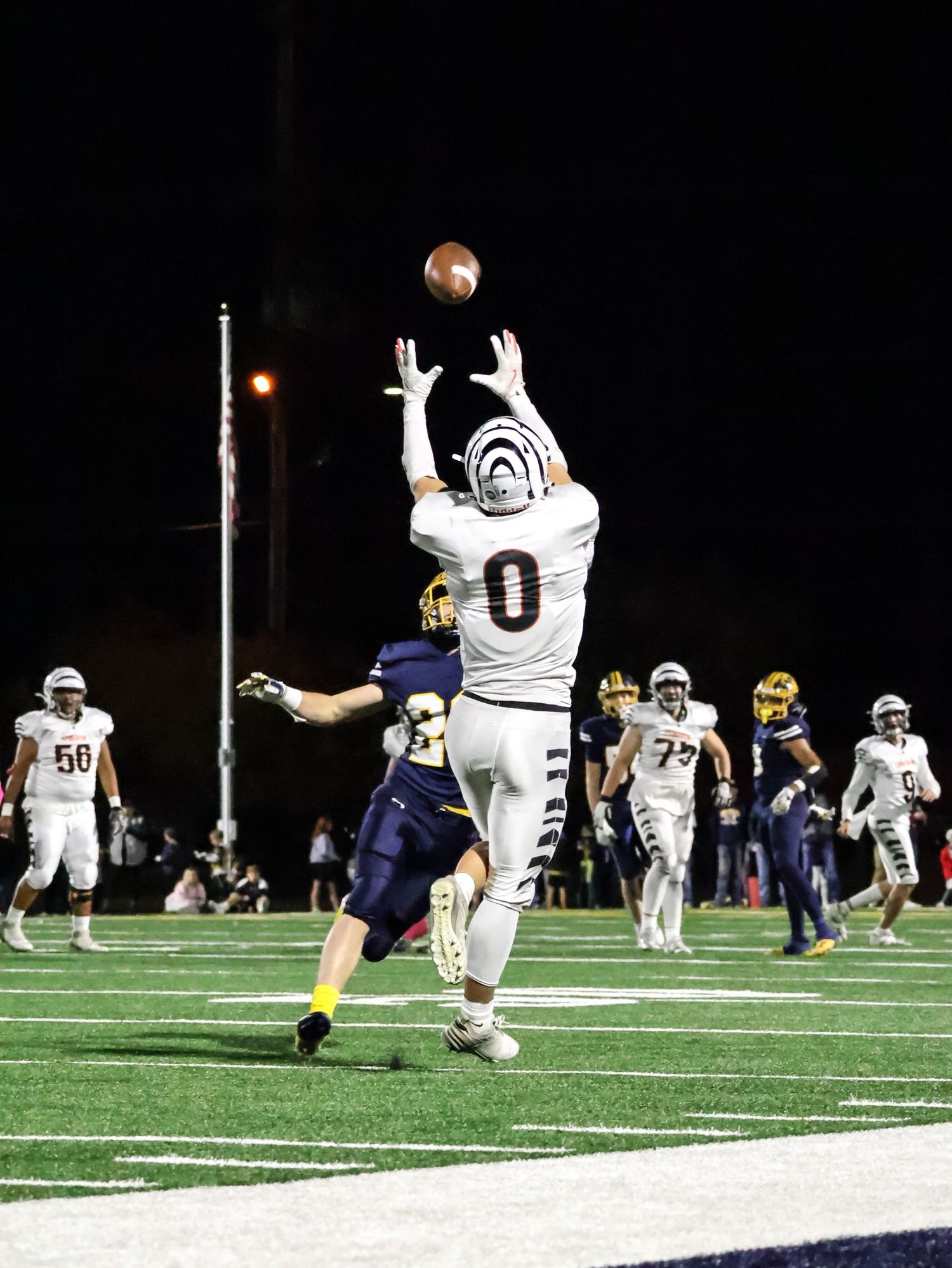 Football players attempting to block a field goal attempt during nighttime game.
