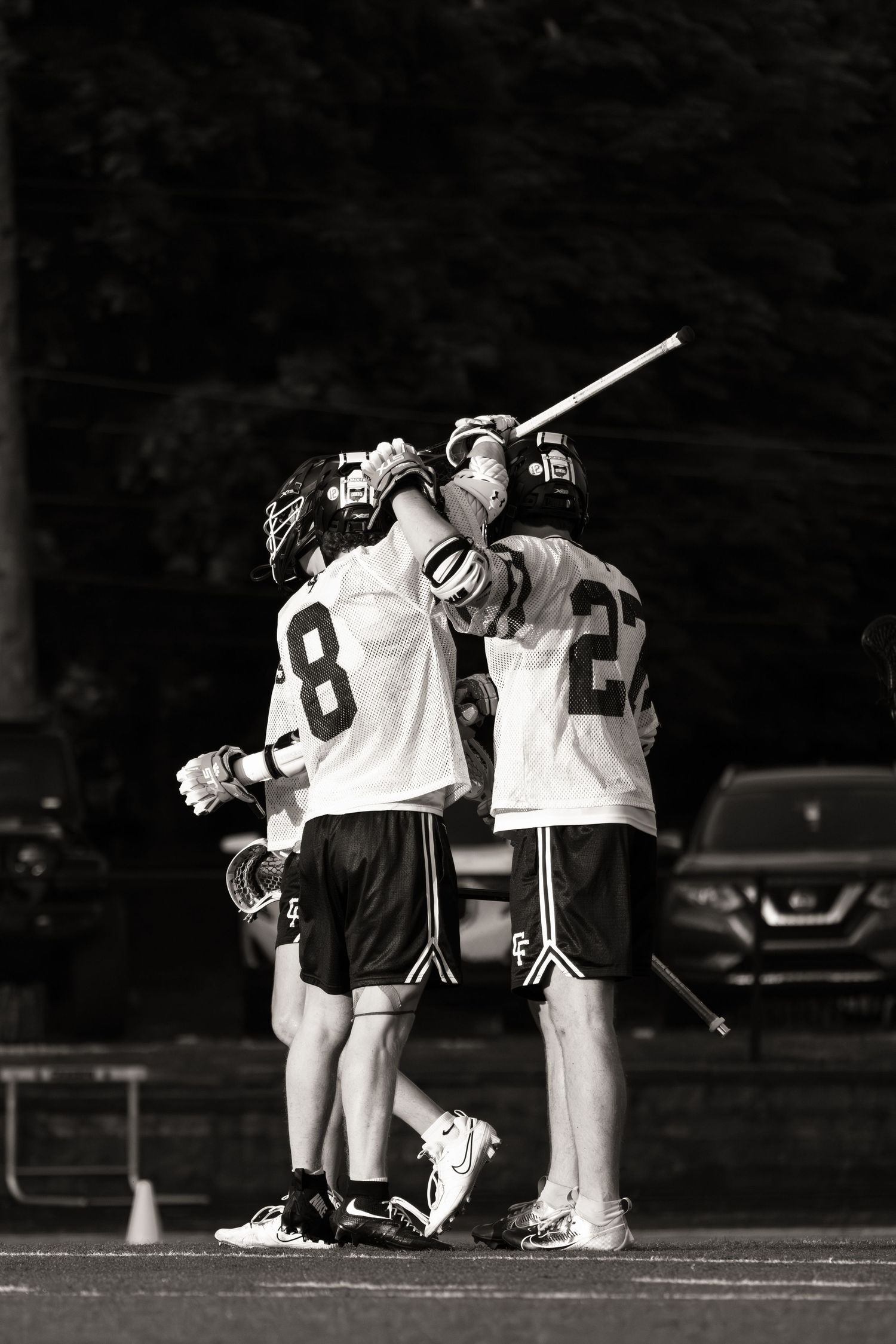 Black and white image showing sports teammates huddling together and consoling each other on a field.