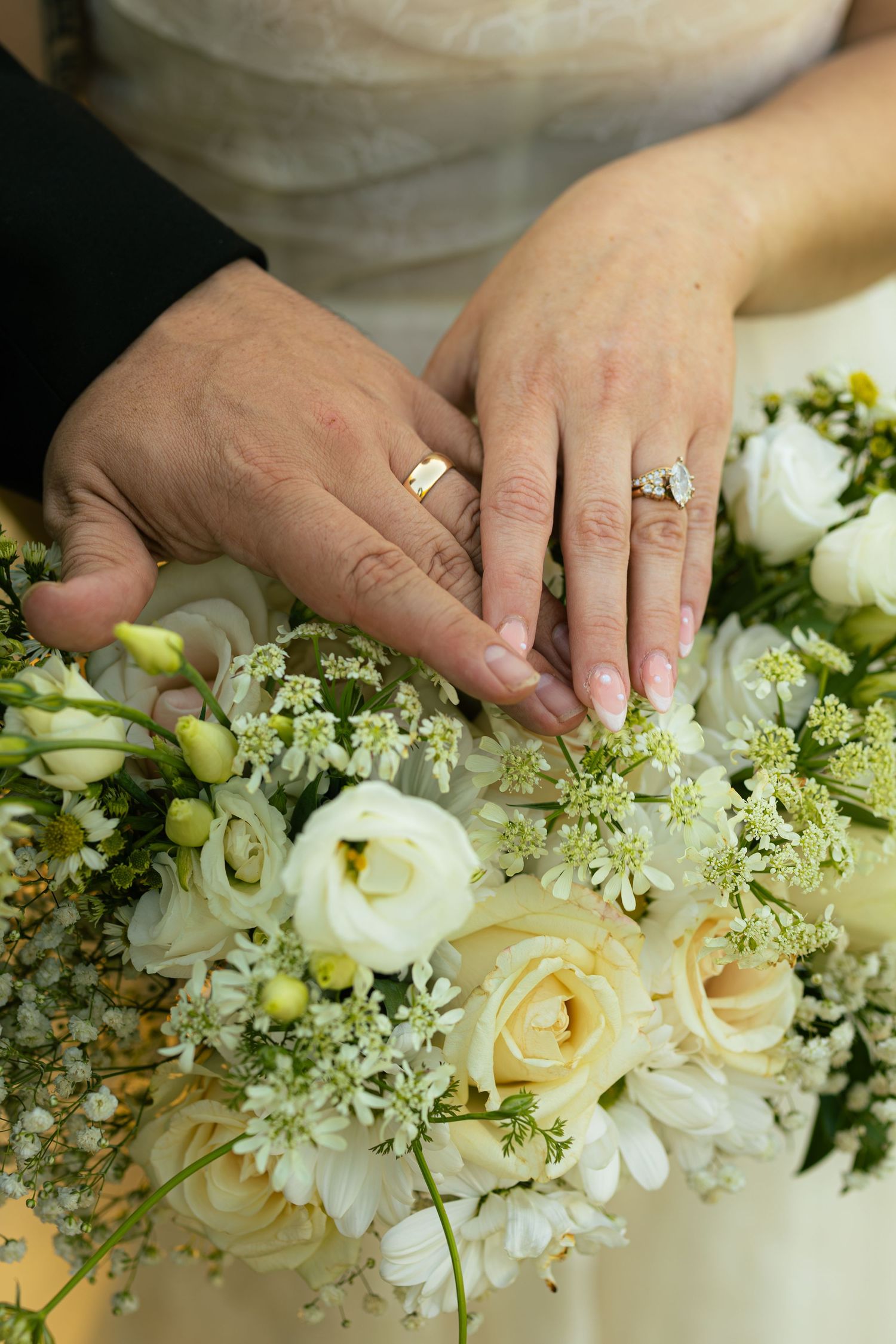 Hands arranging delicate white roses and baby's breath in an elegant floral arrangement.
