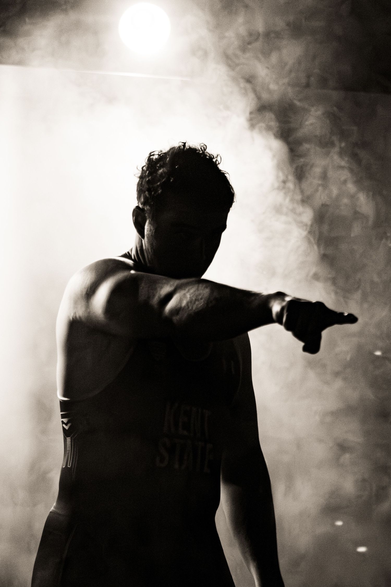 Dramatic silhouettes of performers on stage surrounded by atmospheric smoke effects in black and white photography.