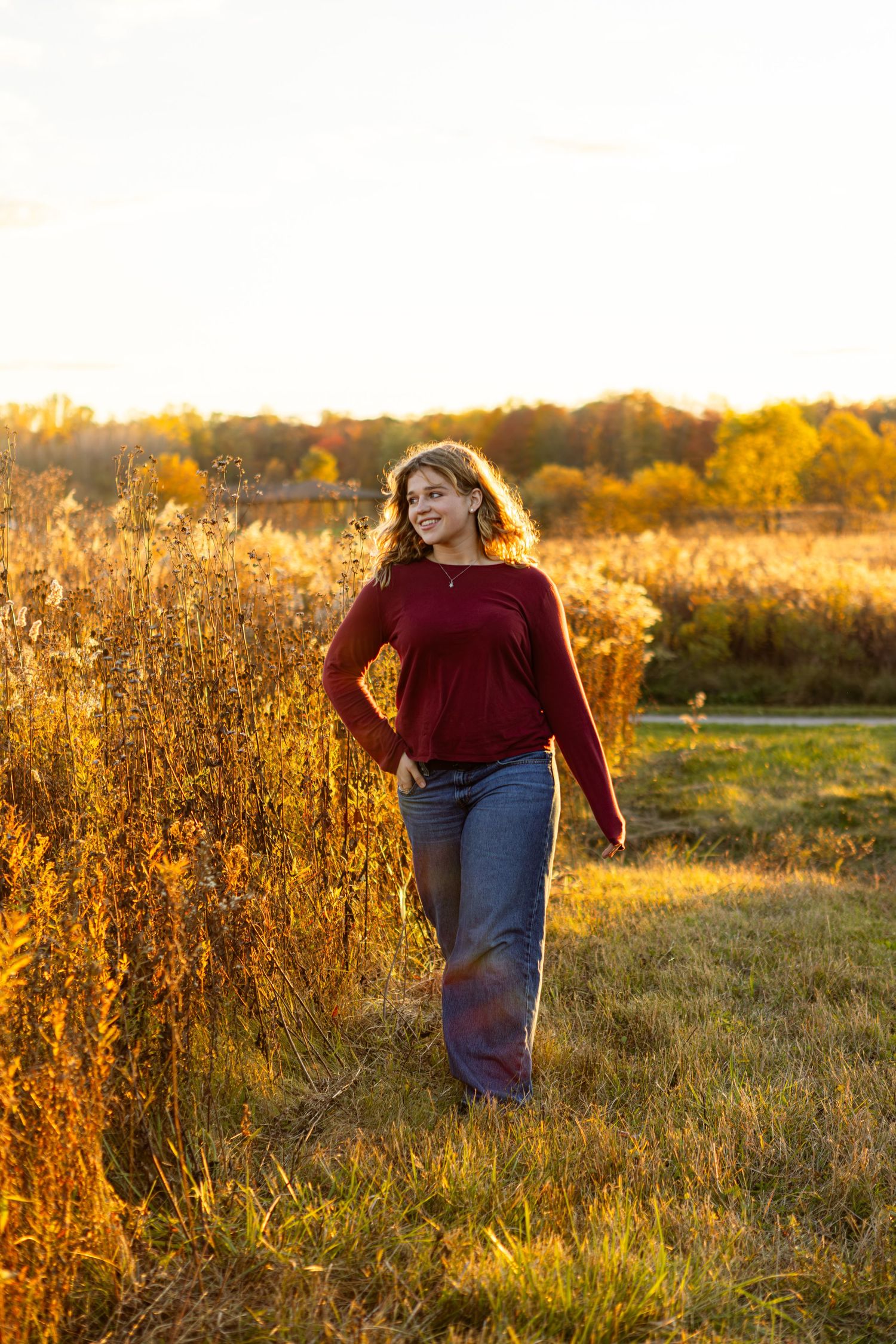A person walks through a golden field at sunset as warm light illuminates the tall grass and wildflowers.