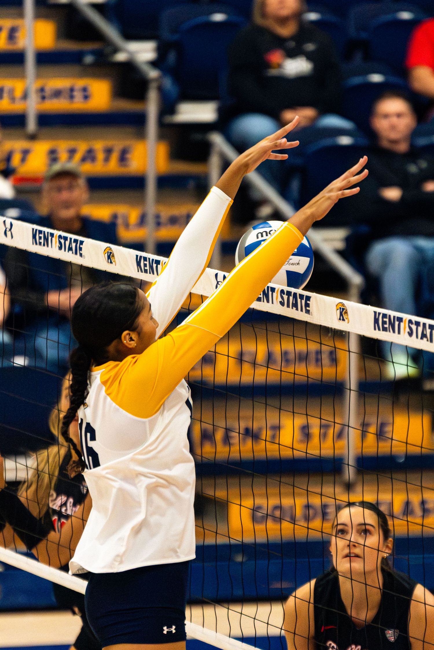 Volleyball players jump at the net to block a shot during an intense match at Kent State.