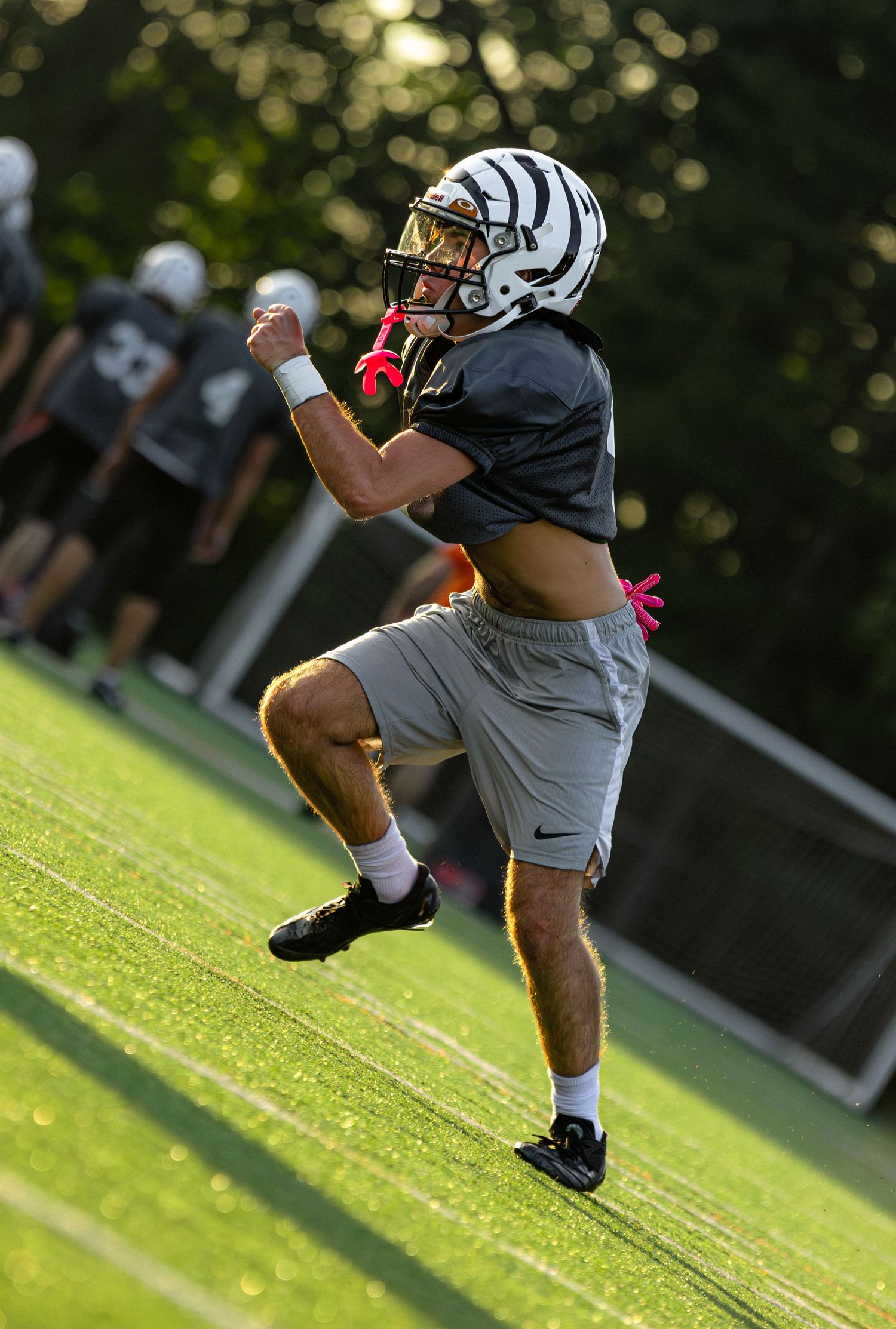 Football player practicing kicking drills on a sunny green field.