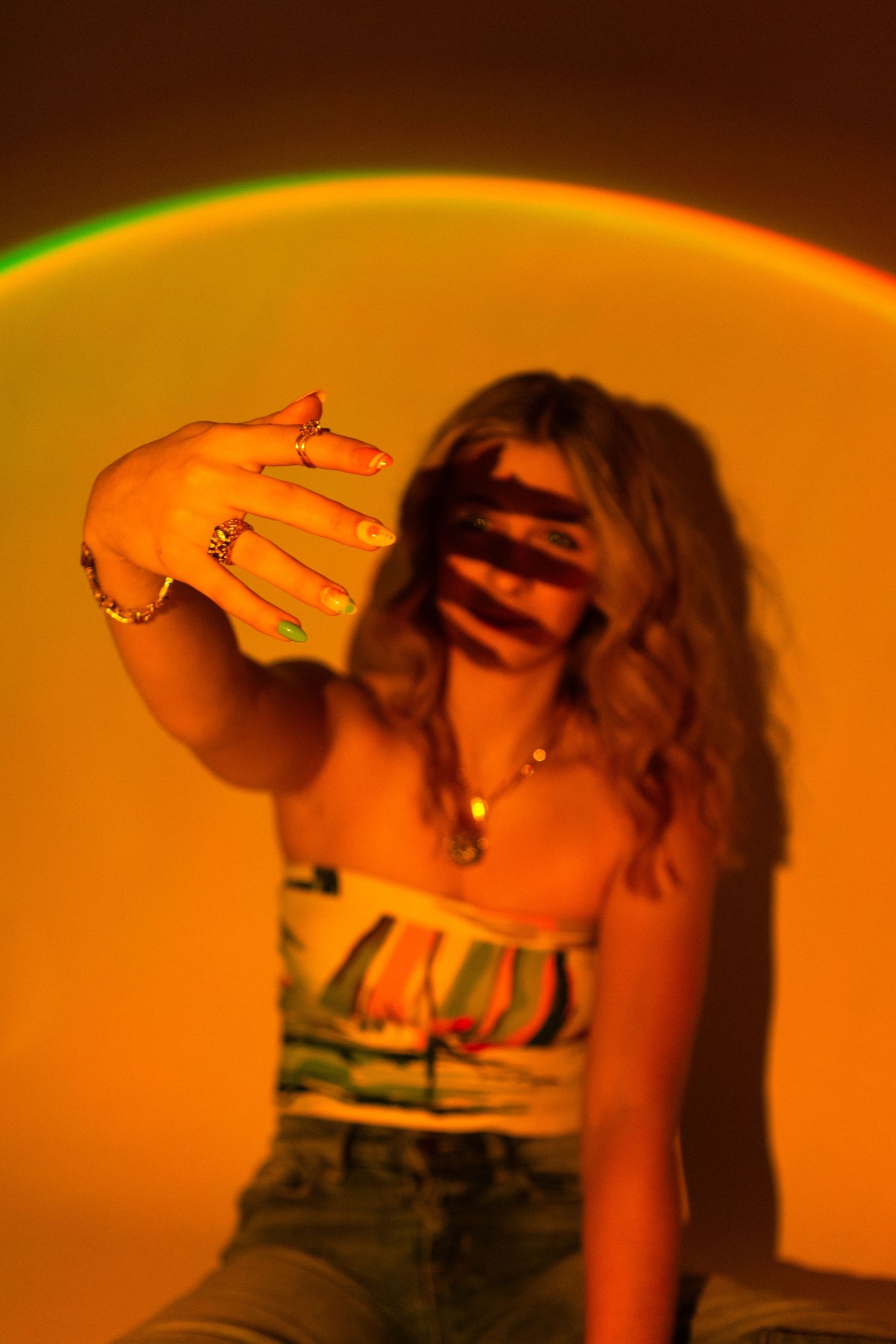 Creative portrait with orange backlight and hand casting shadow patterns.
