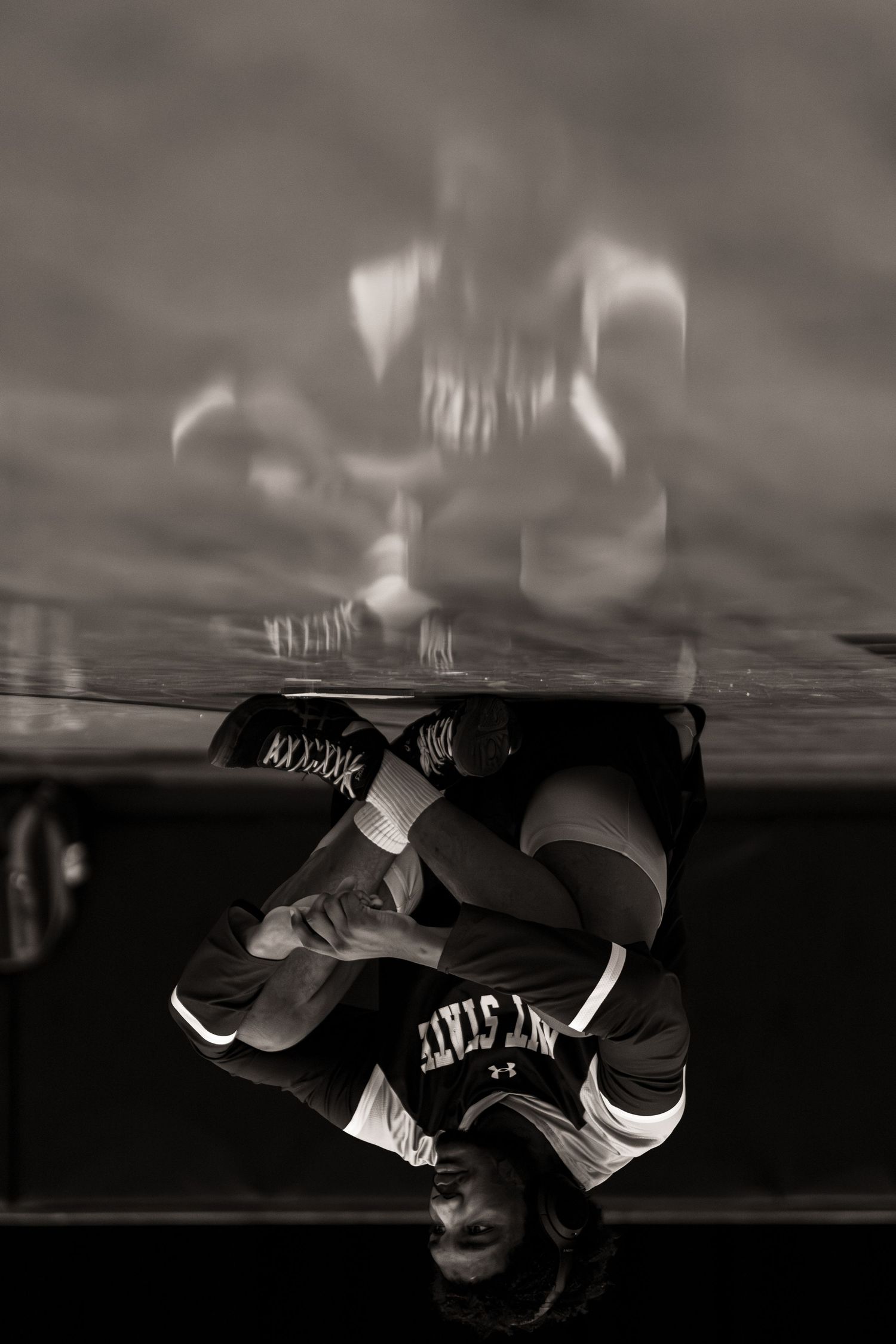 Black and white photo sequence shows a skateboarder performing an aerial flip trick against a dramatic cloudy sky.