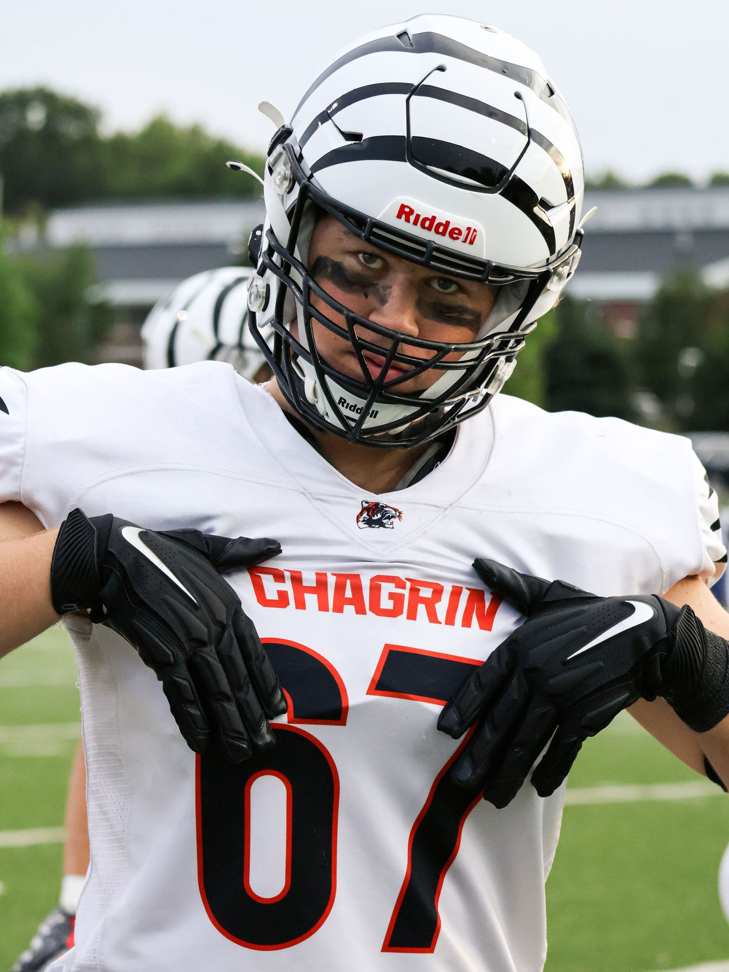 Football players in white jerseys with Chagrin text celebrate on the field.