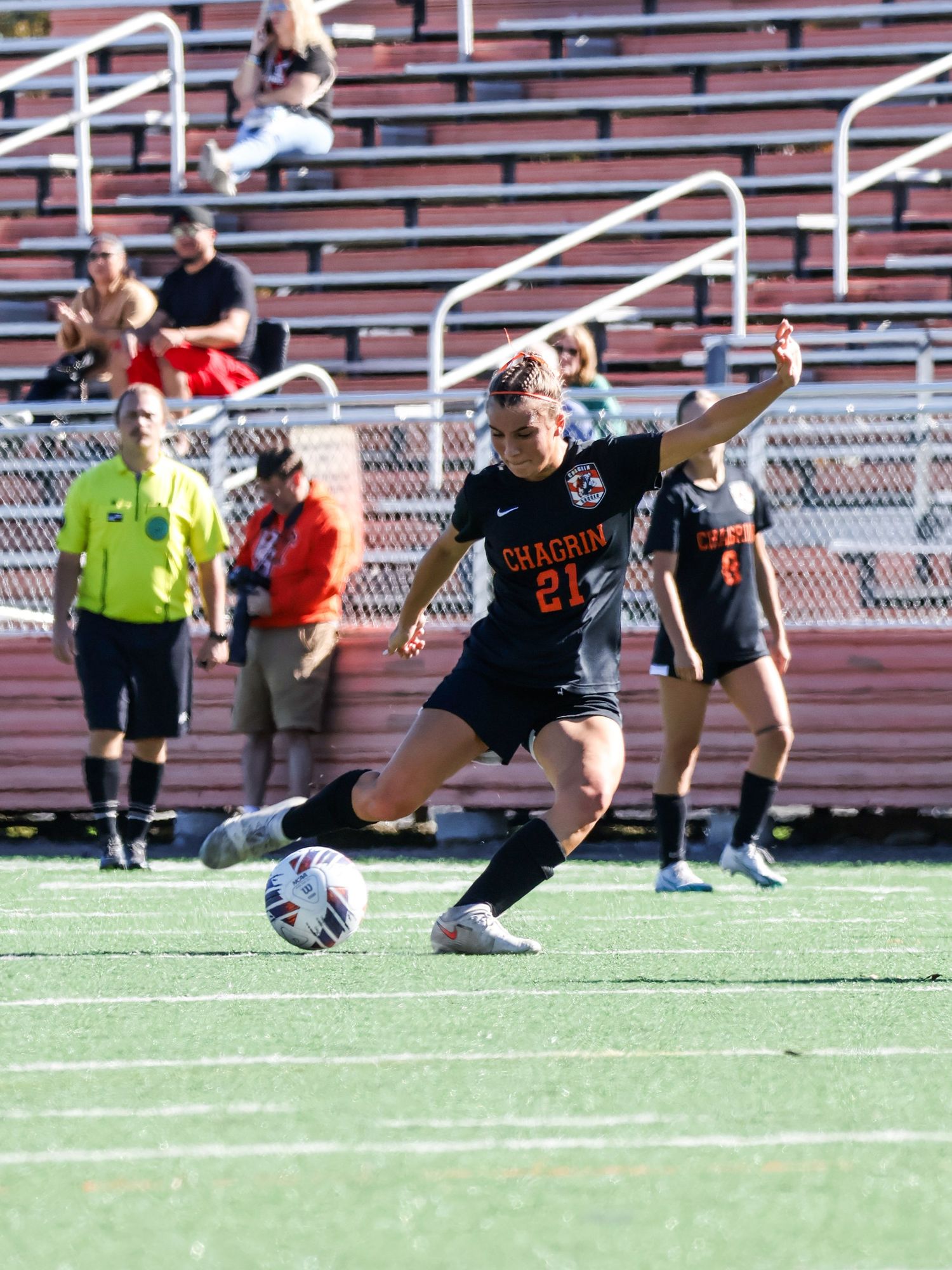 Soccer player in black jersey preparing to kick ball on athletic field.