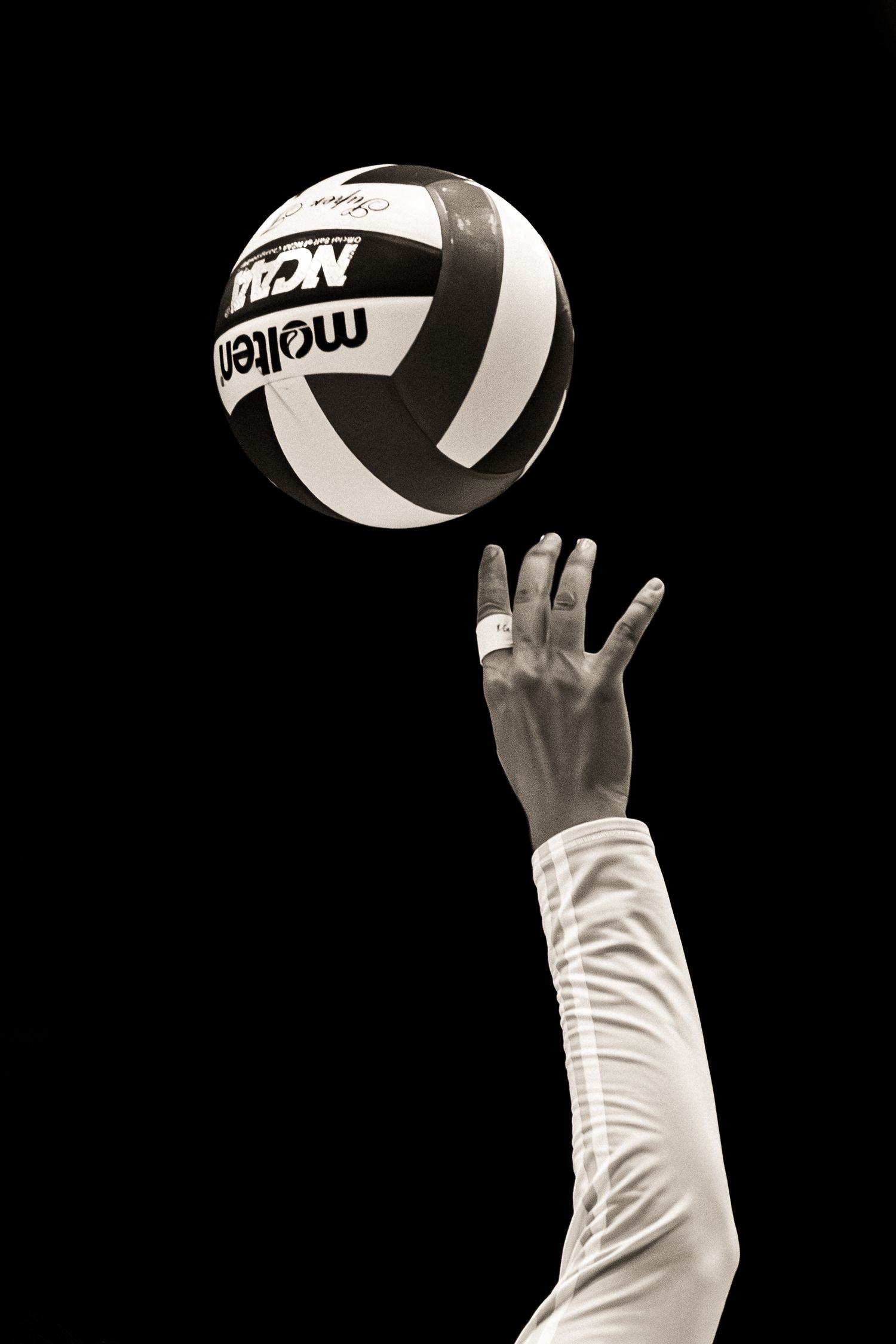 A sequence of black and white photos showing a volleyball being served with an upraised arm against a dark background.