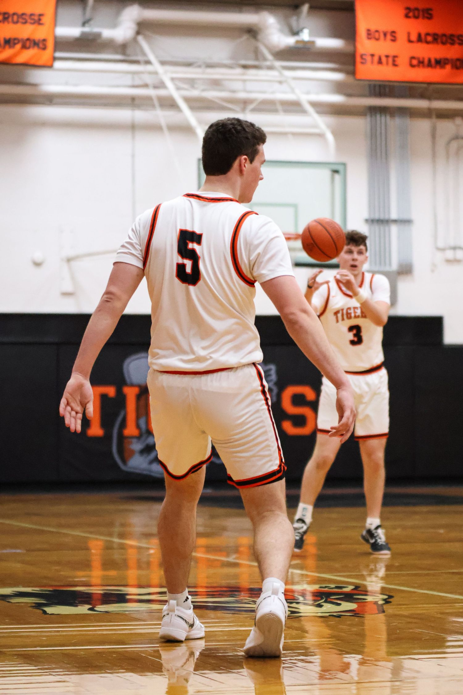 Basketball players in white uniforms on a wooden court during a game.