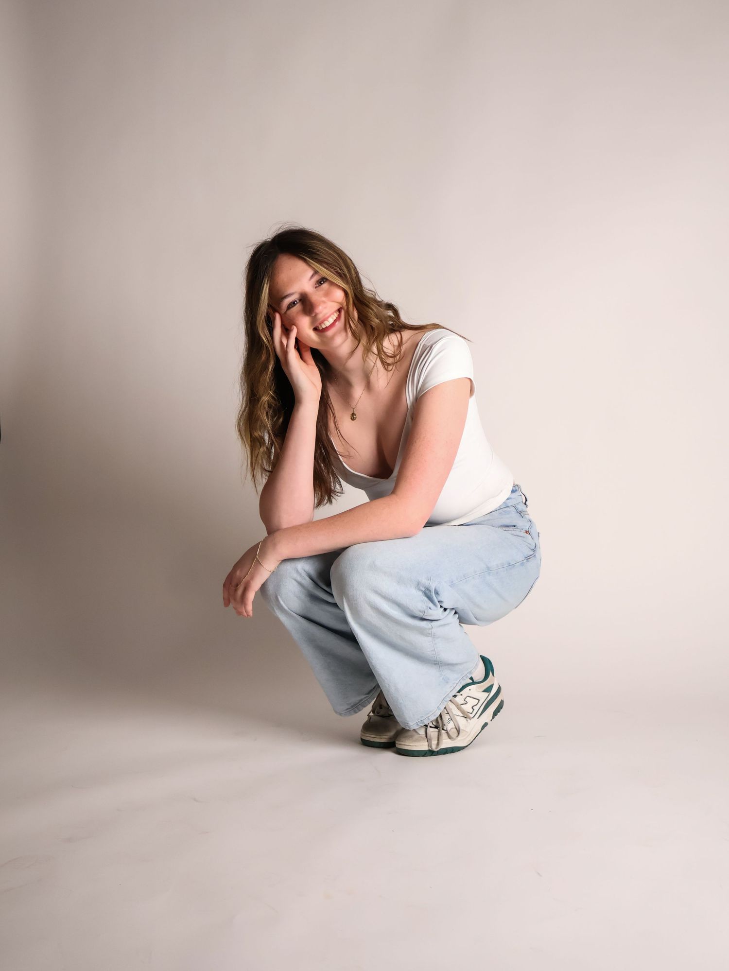 A person in casual wear sits and poses expressively against a plain background in a minimalist photo series.