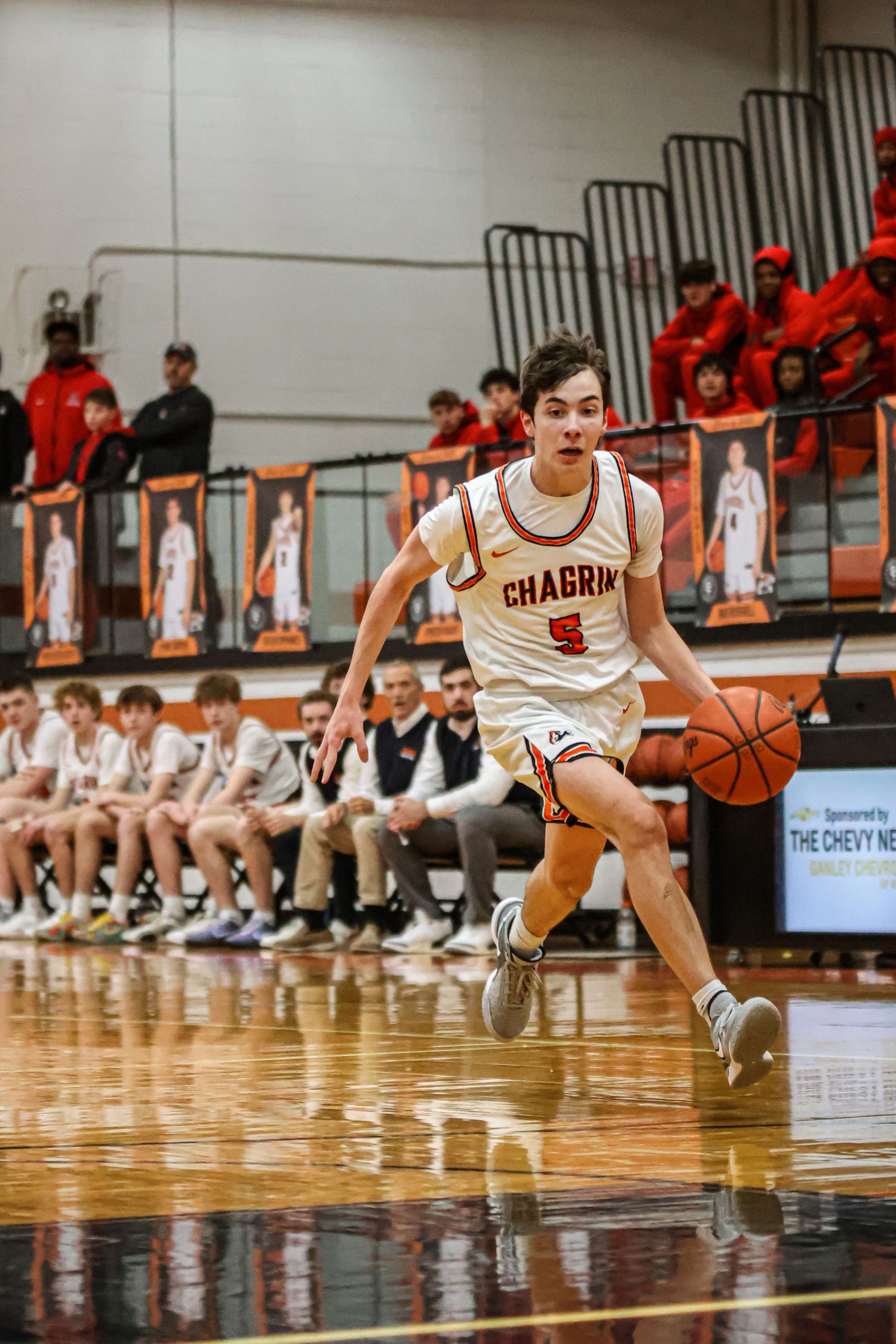 Basketball player dribbles low to the court during fast break play.