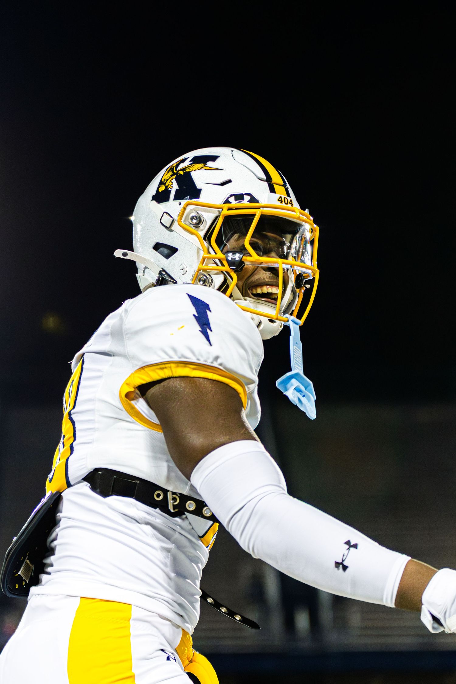 Football player in white and gold uniform celebrates during a game with an energetic sideline celebration.