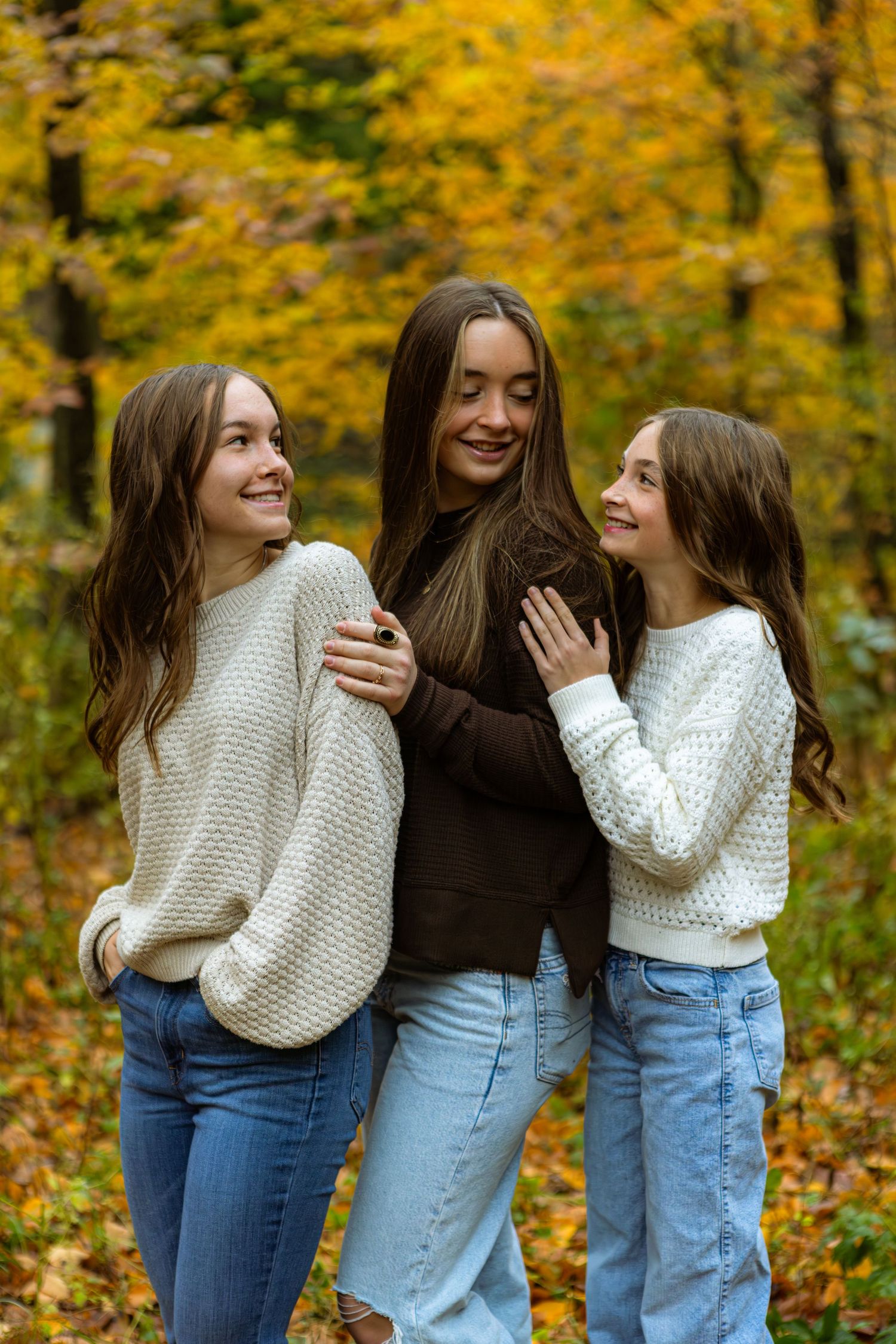 Friends share laughter and hugs in a series of candid moments against vibrant autumn foliage background.