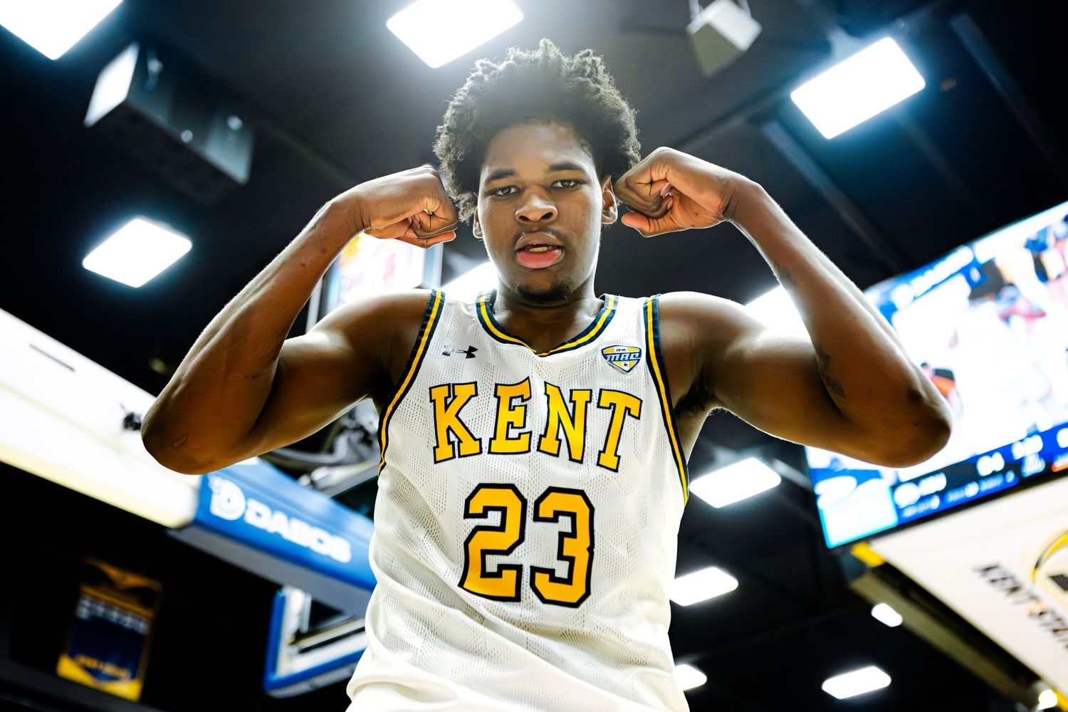 Kent State basketball player #23 flexing in white jersey during game.