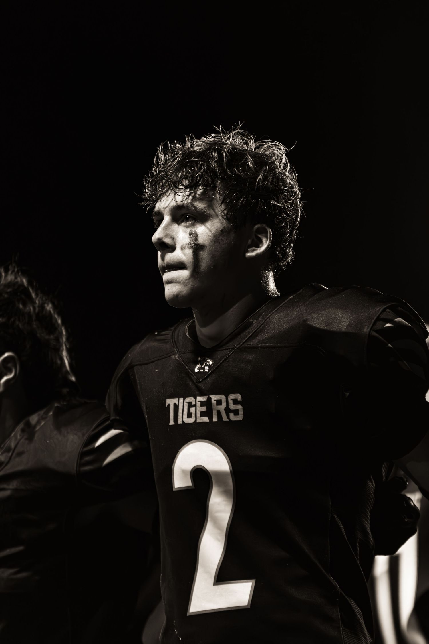Black and white photo of a Tigers football player wearing jersey number 2, looking intense under dramatic lighting.