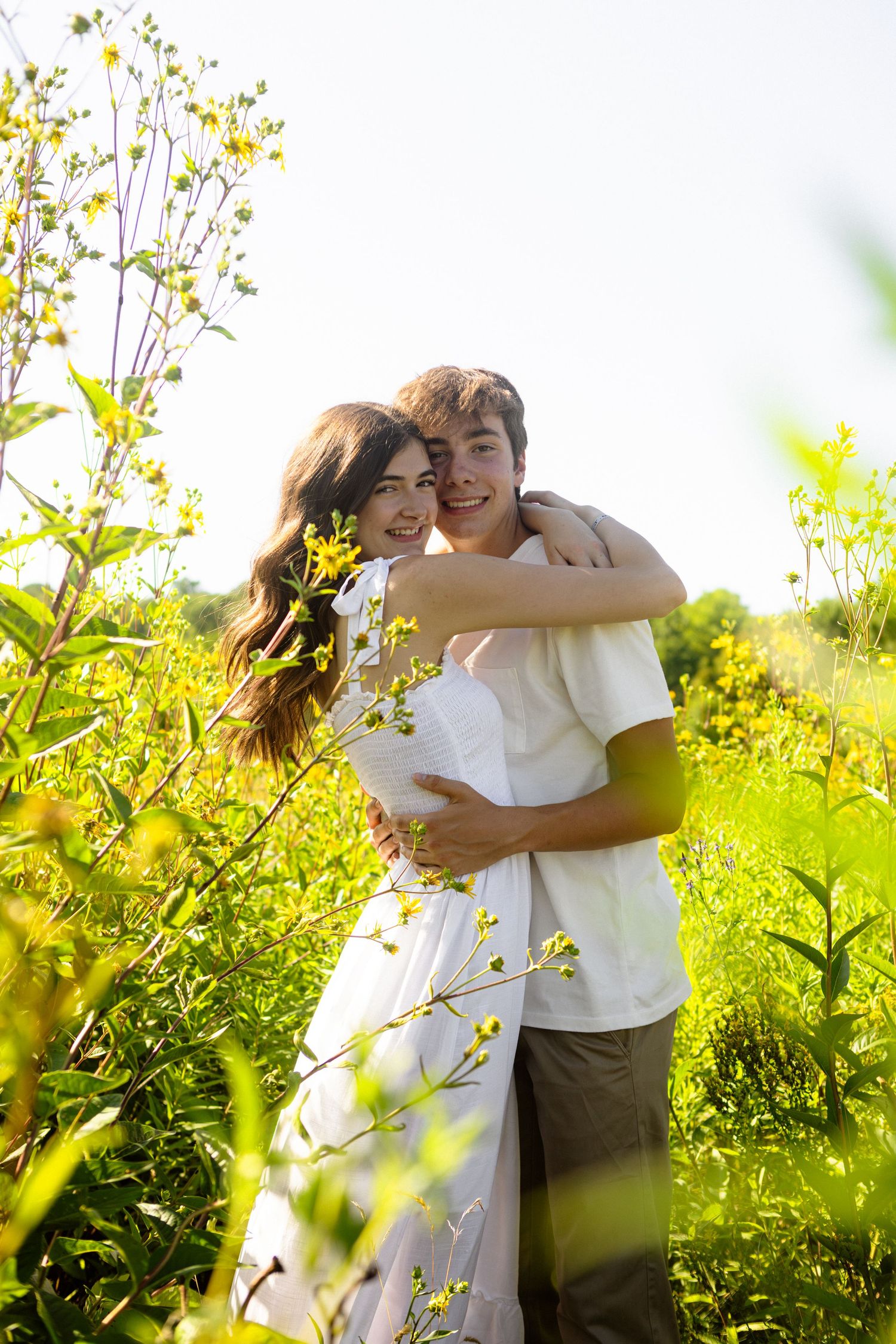 A romantic moment outdoors surrounded by blooming yellow wildflowers on a sunny summer day.