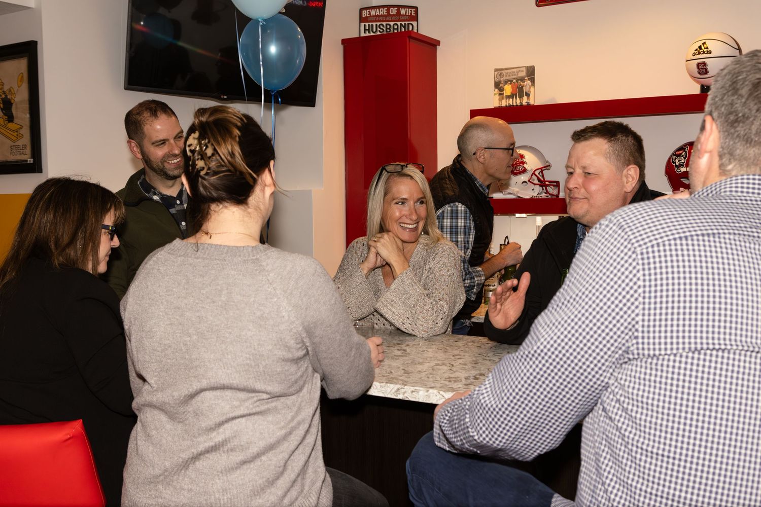 Social gathering at a restaurant with people sitting around a table engaged in conversation.