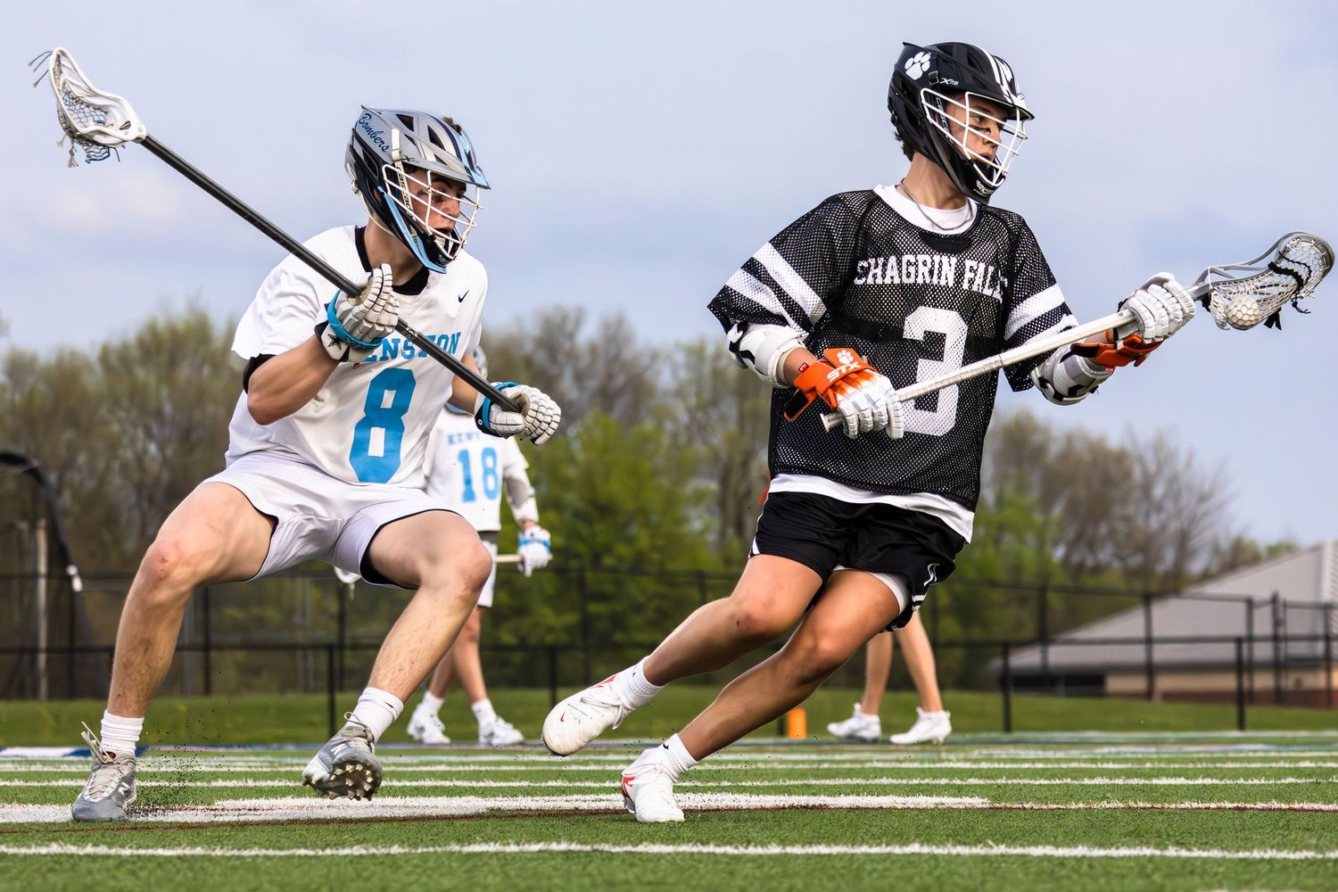 Two lacrosse players from opposing teams compete for ball during match.