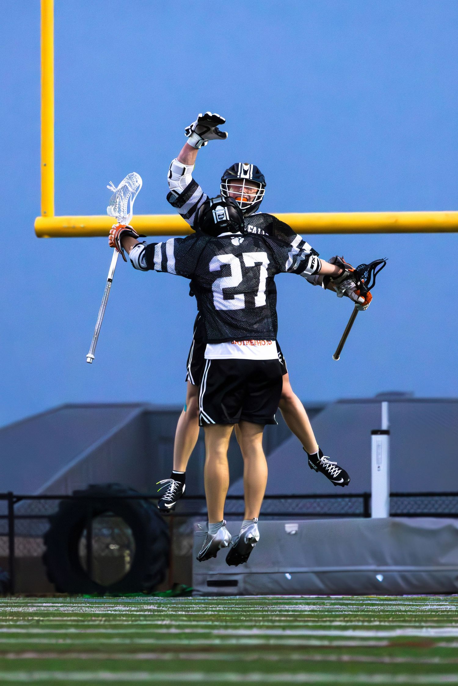 Football player in navy and white uniform jumps to celebrate near yellow goal post.